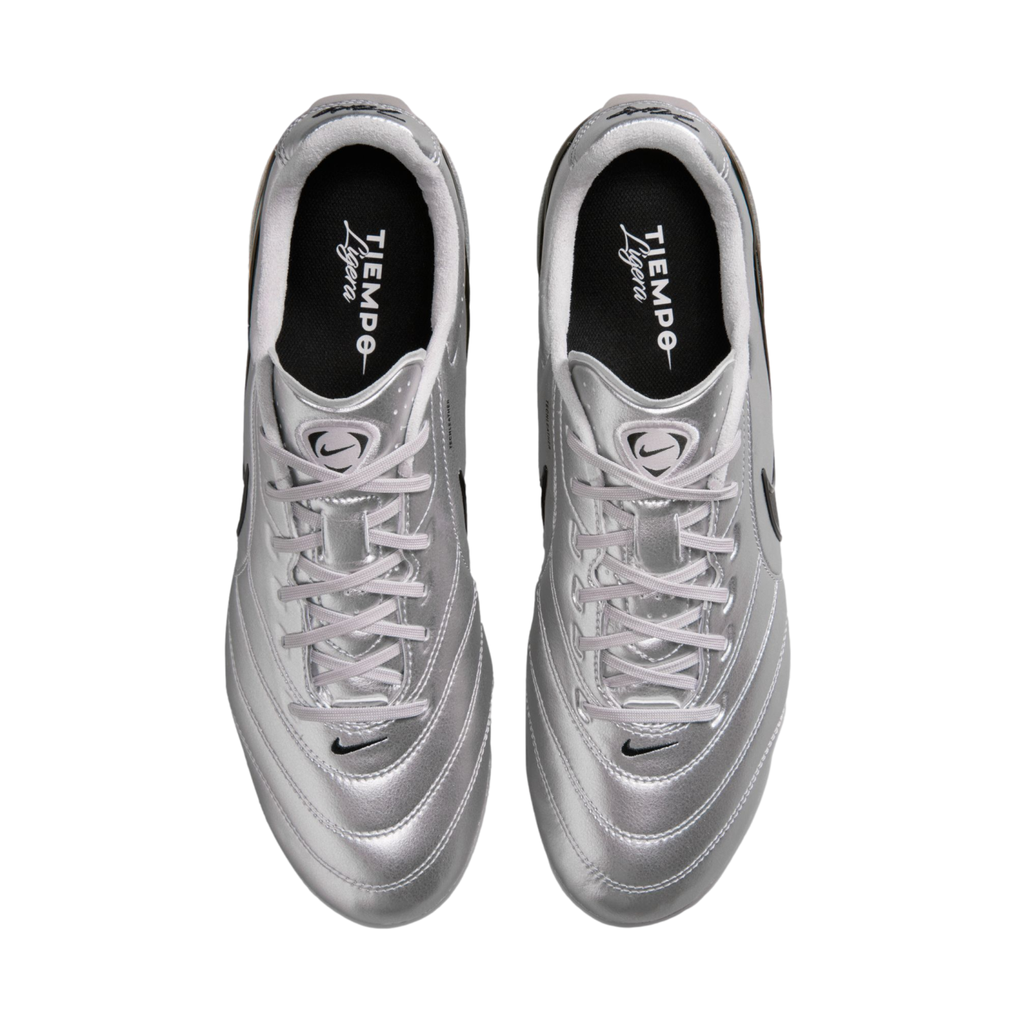 A top-down view of a pair of metallic silver Nike Tiempo Ligera soccer shoes with white laces and black insoles, set against a solid black background.