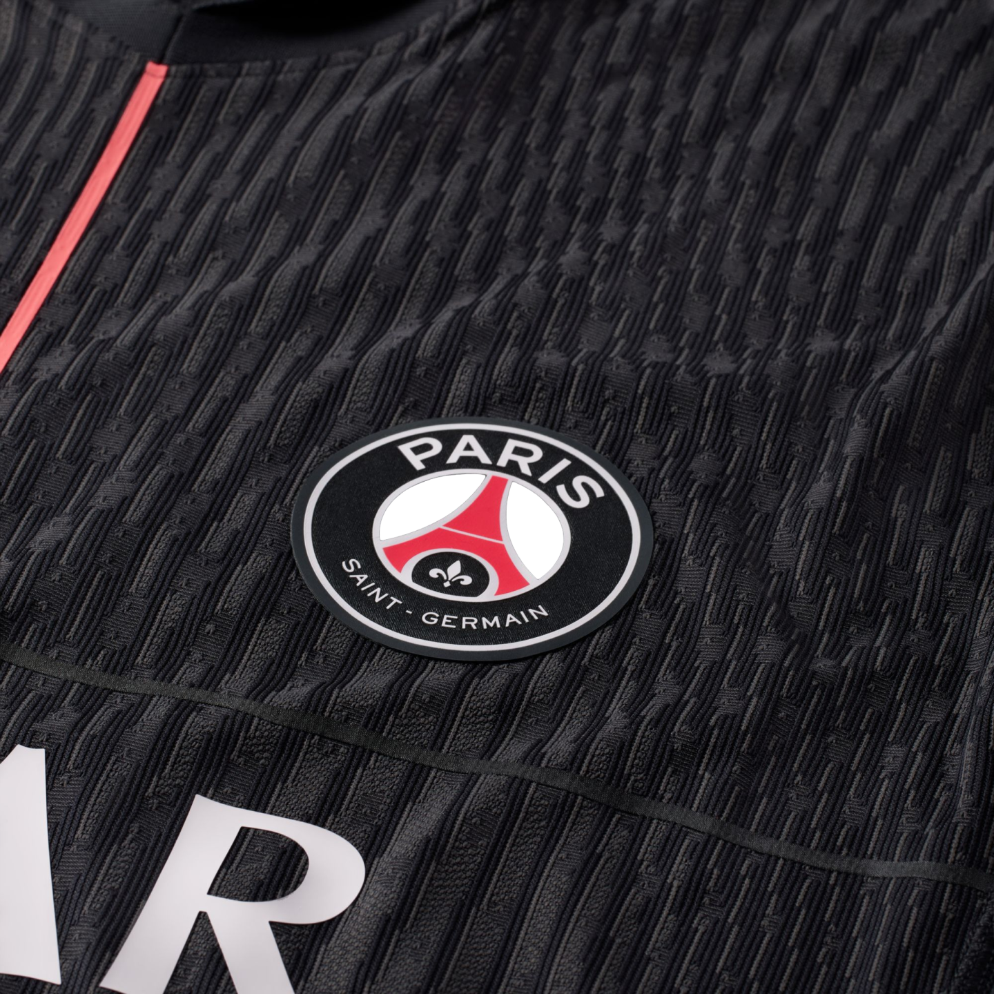 Close-up of a black textured Paris Saint-Germain soccer jersey featuring the club's circular crest.