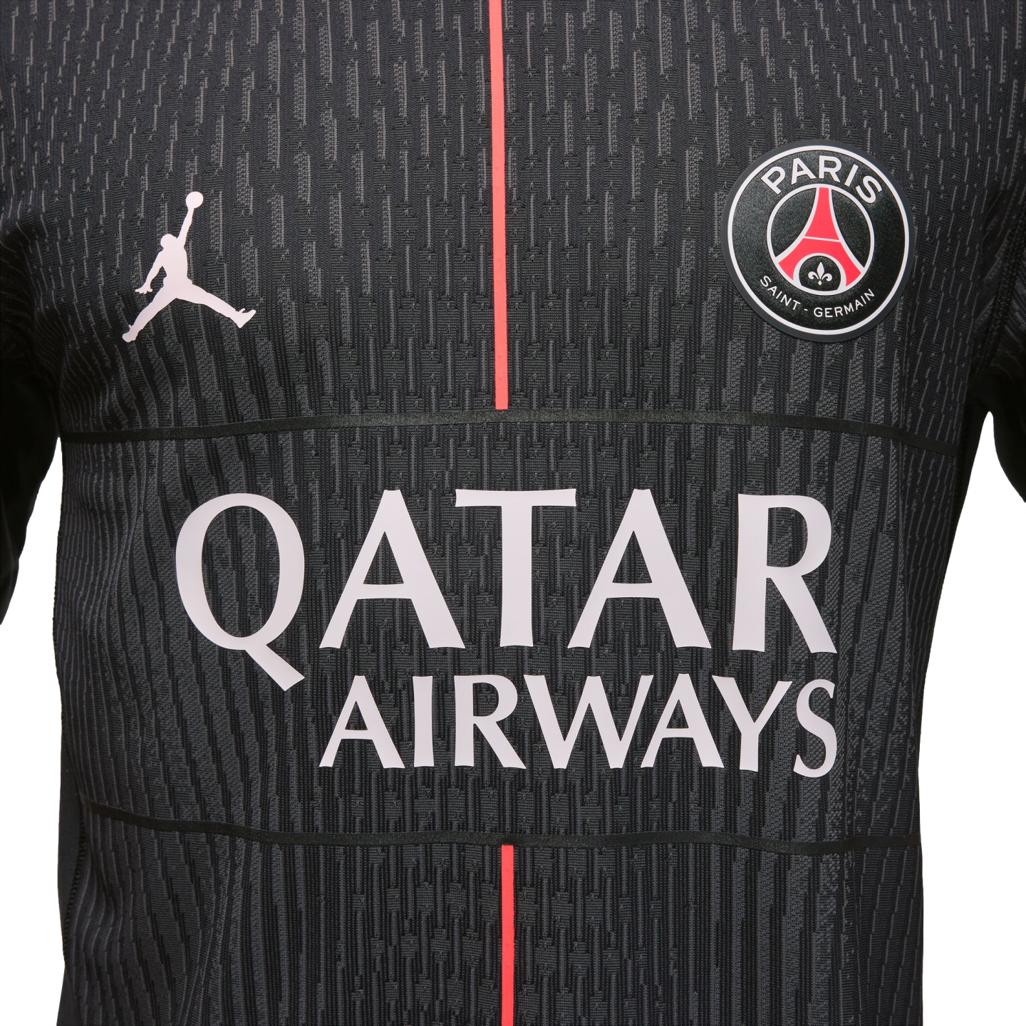 Close-up of a black Jordan PSG jersey featuring the club crest, Jumpman logo, red vertical stripe, and white "QATAR AIRWAYS" text on a textured fabric.