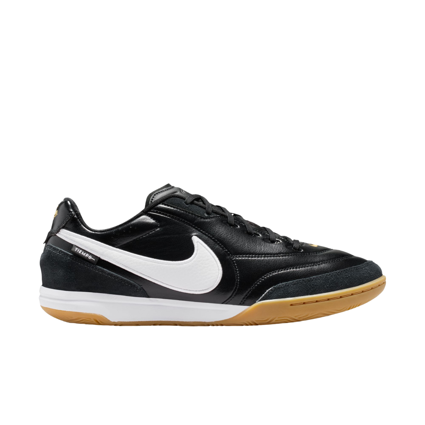 Profile of a black Nike Tiempo indoor soccer shoe with a white swoosh, white midsole, and gum rubber outsole, displayed against a black background.