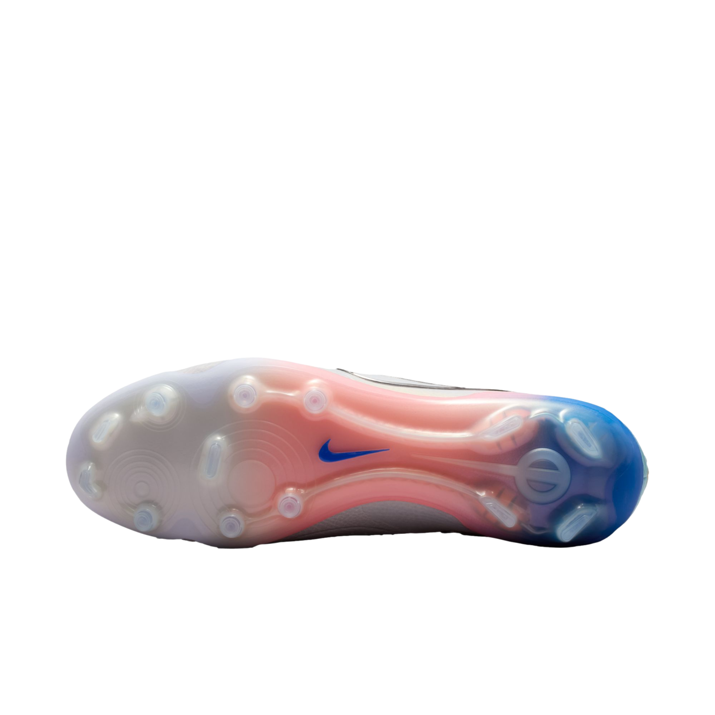 The translucent sole of a soccer cleat fades from white to pink to blue, featuring clear studs and a small blue Nike swoosh against a solid black background.