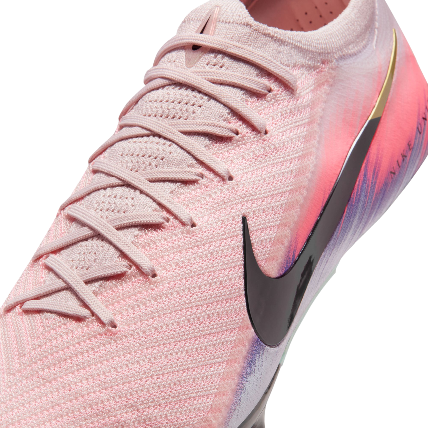 Close-up of a pink Nike soccer cleat with a black swoosh logo and textured knit upper against a black background.