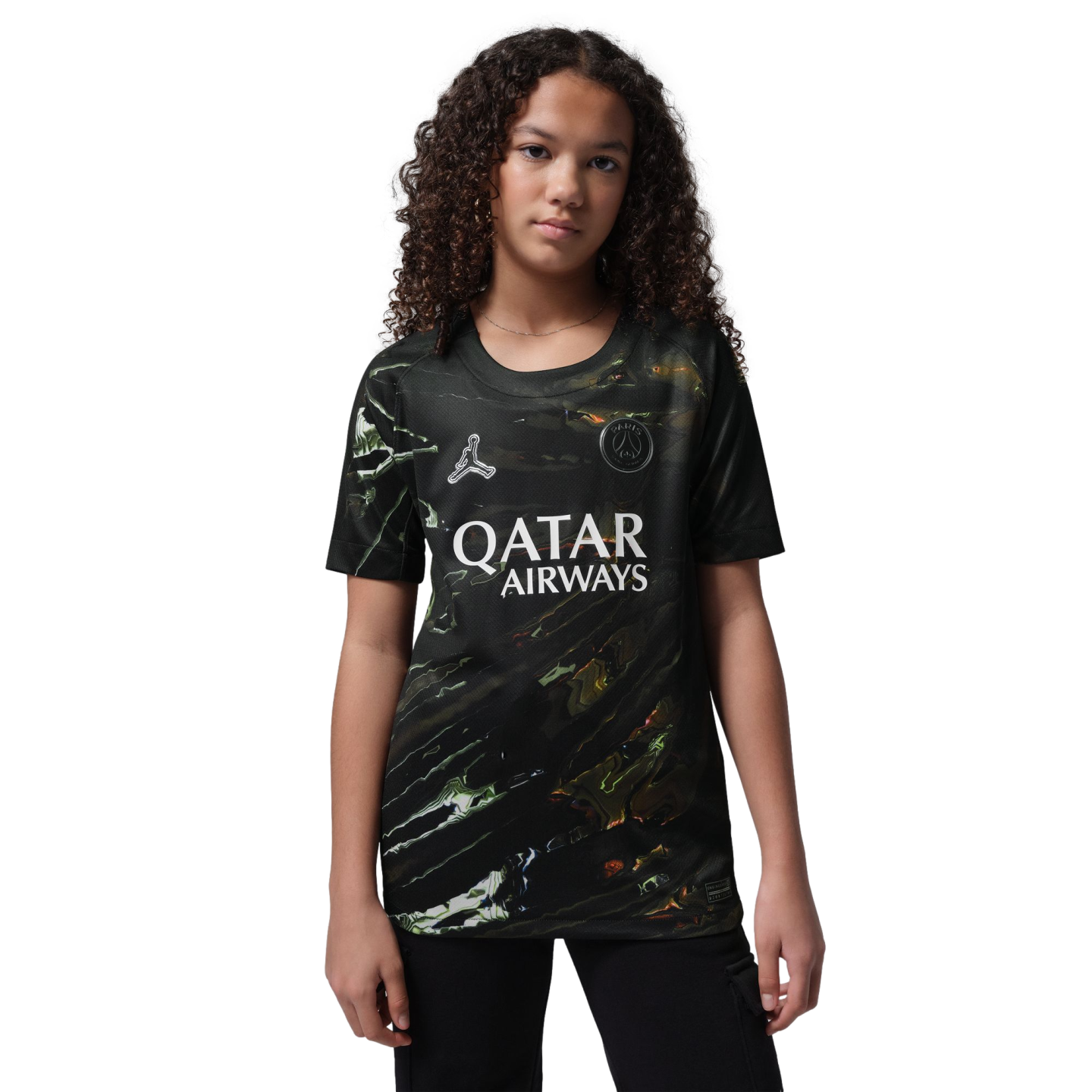 A young person with curly hair wearing a black marbled Paris Saint-Germain soccer jersey, standing against a black background.