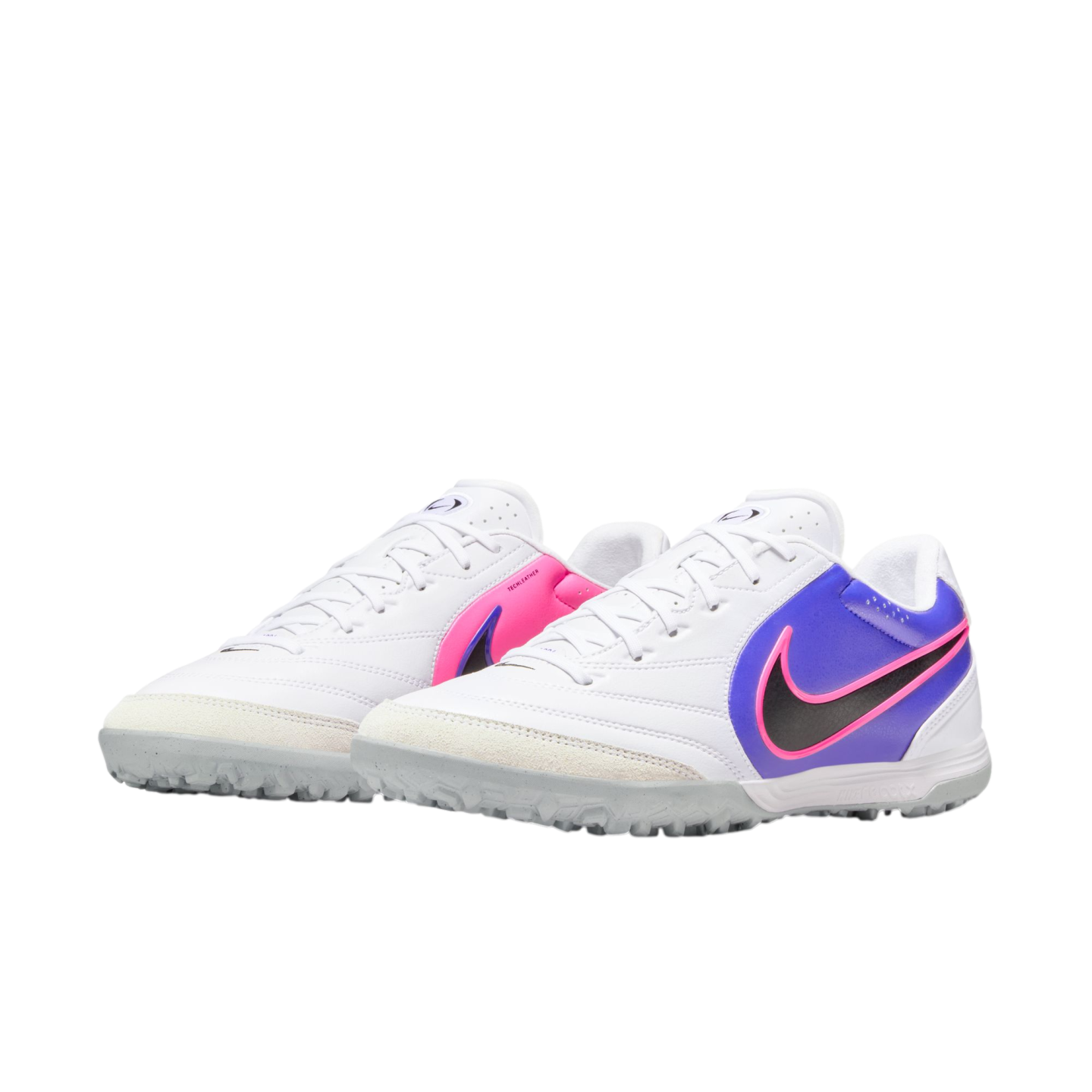 A pair of white Nike turf soccer shoes featuring vibrant purple and pink side accents and black swoosh logos.