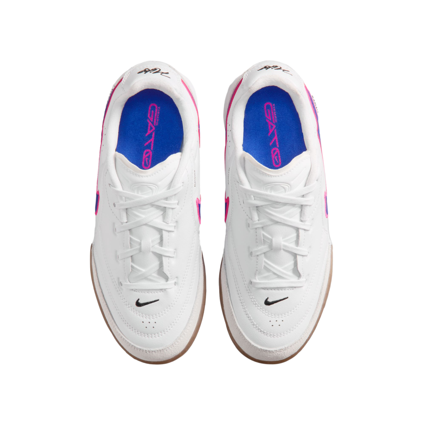 Top-down view of white Nike Gato indoor soccer shoes with blue insoles and pink accents, set against a black background.