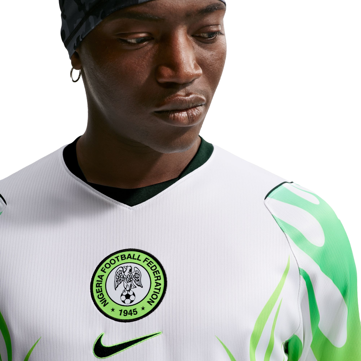 Close-up of a man wearing a white Nigeria national football team jersey with green leaf-patterned sleeves and the federation crest on the chest.