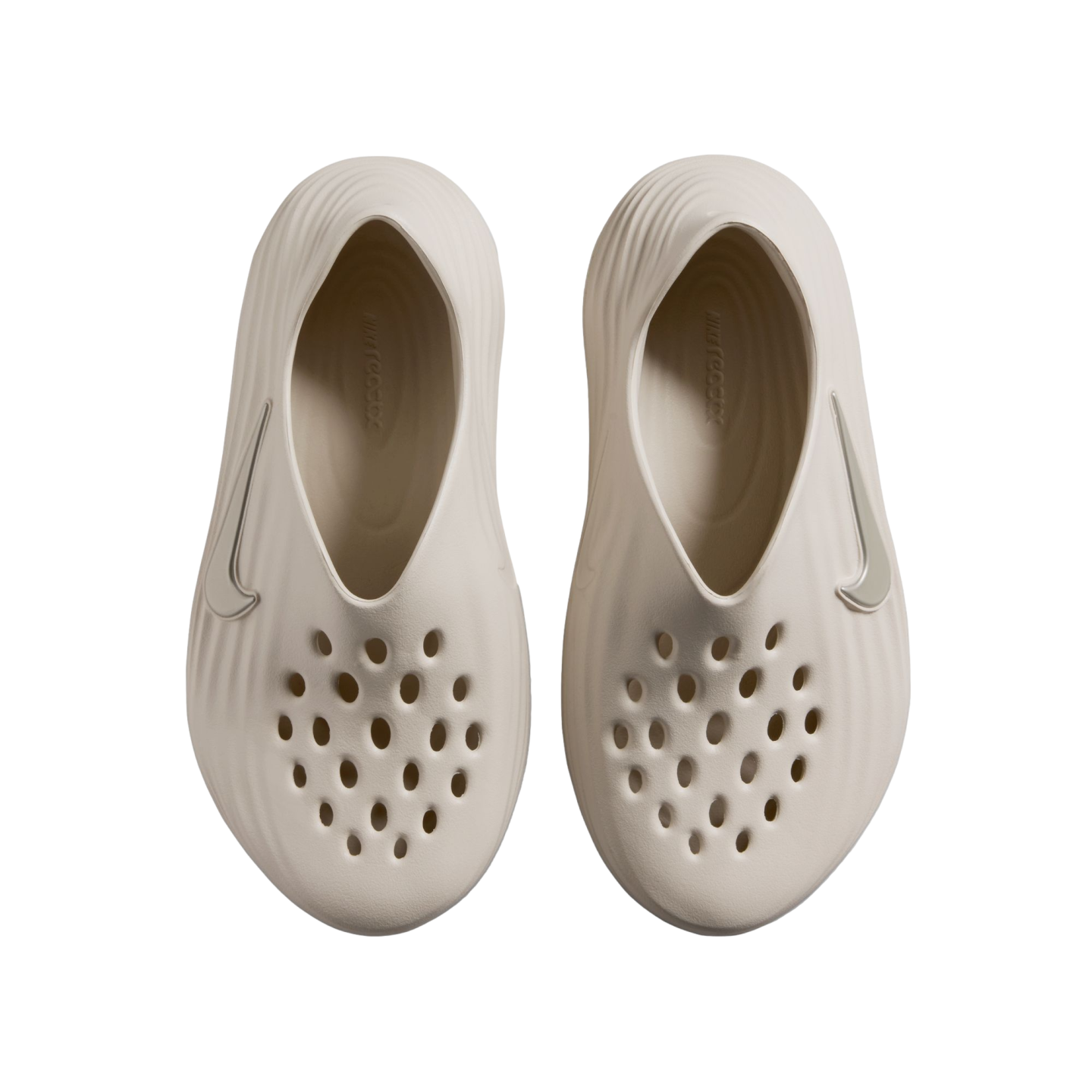 Top-down view of a pair of beige Nike foam clogs with perforated toes and textured sides, set against a black background.
