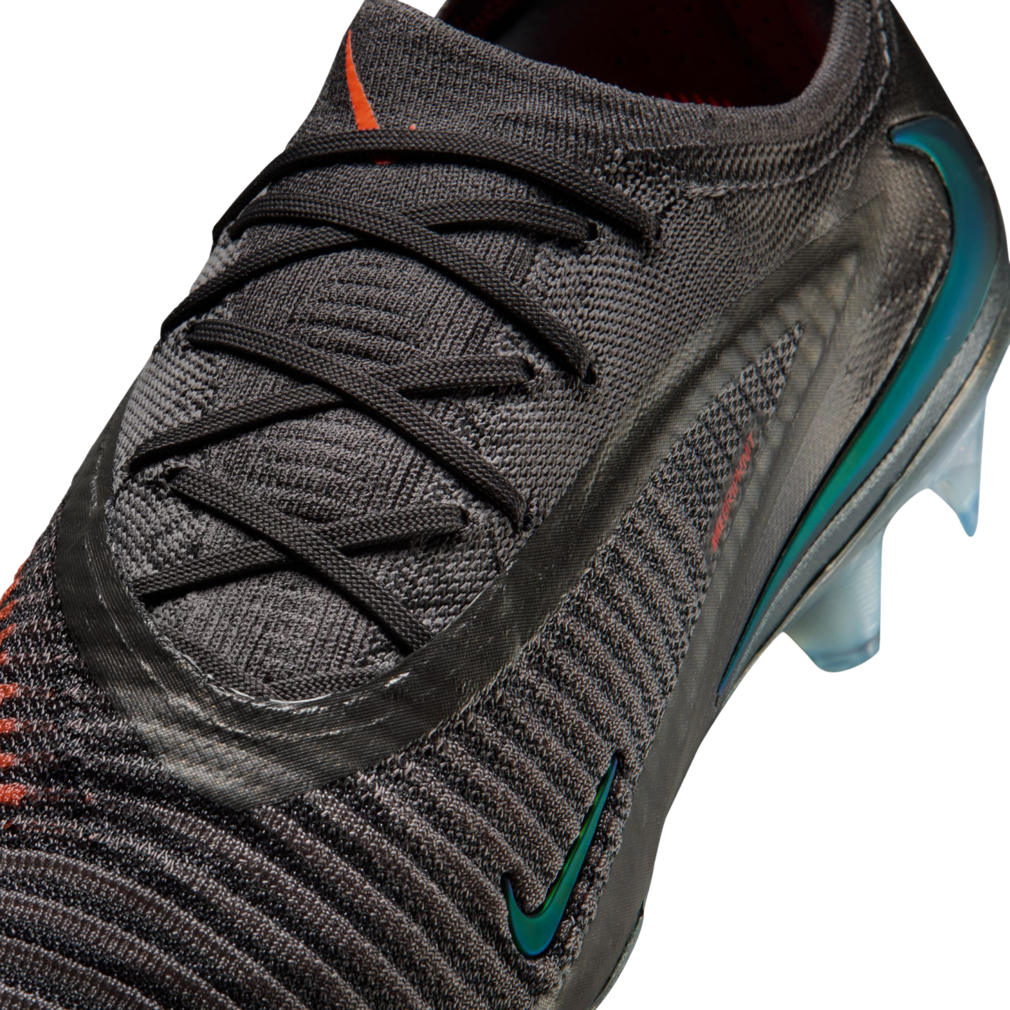 Close-up of a dark grey Nike soccer cleat with a textured knit upper, black laces, and an iridescent Nike swoosh on the side.
