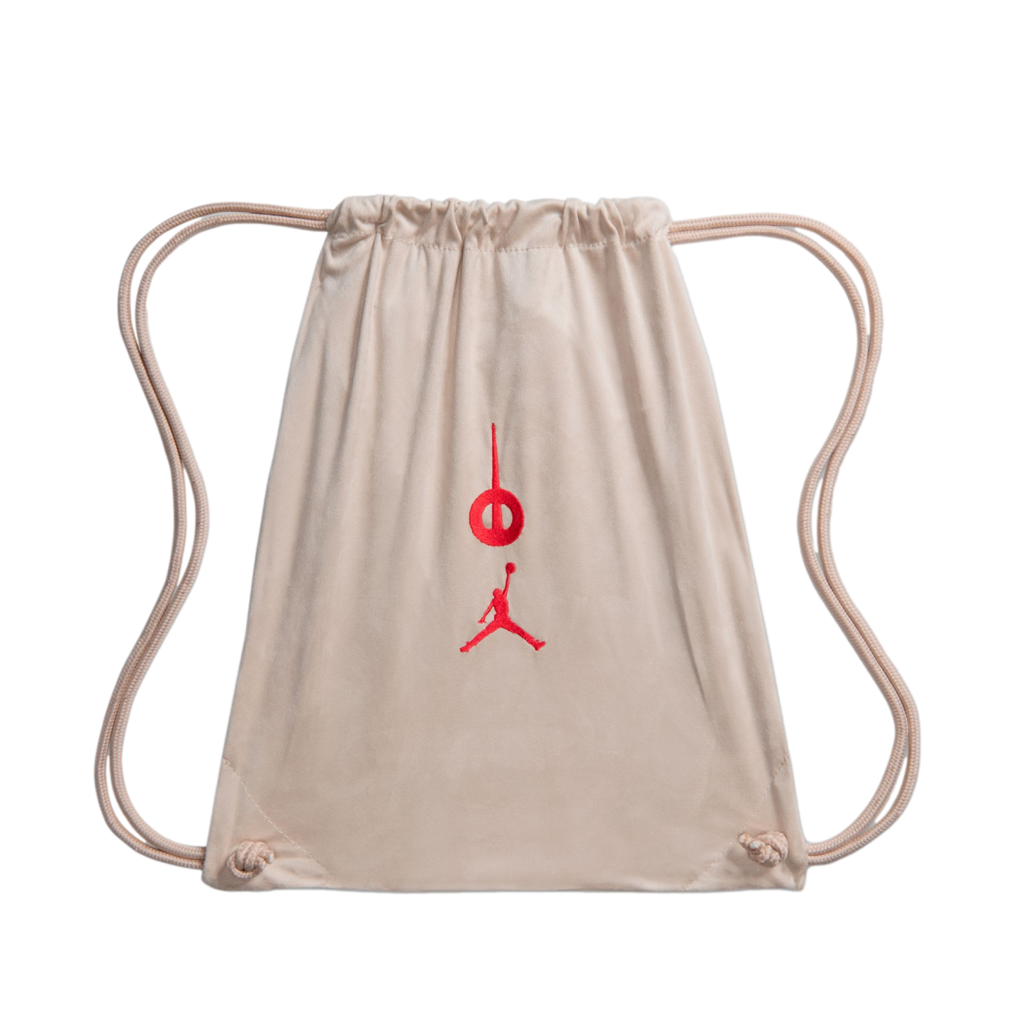 A light tan suede drawstring bag with a red embroidered Jordan Jumpman and a circular logo on the front, isolated on a black background.