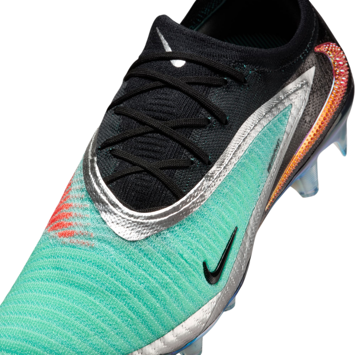 Close-up of a Nike soccer cleat with a teal textured upper, black lace area, metallic silver trim, and a large iridescent orange swoosh on the heel.
