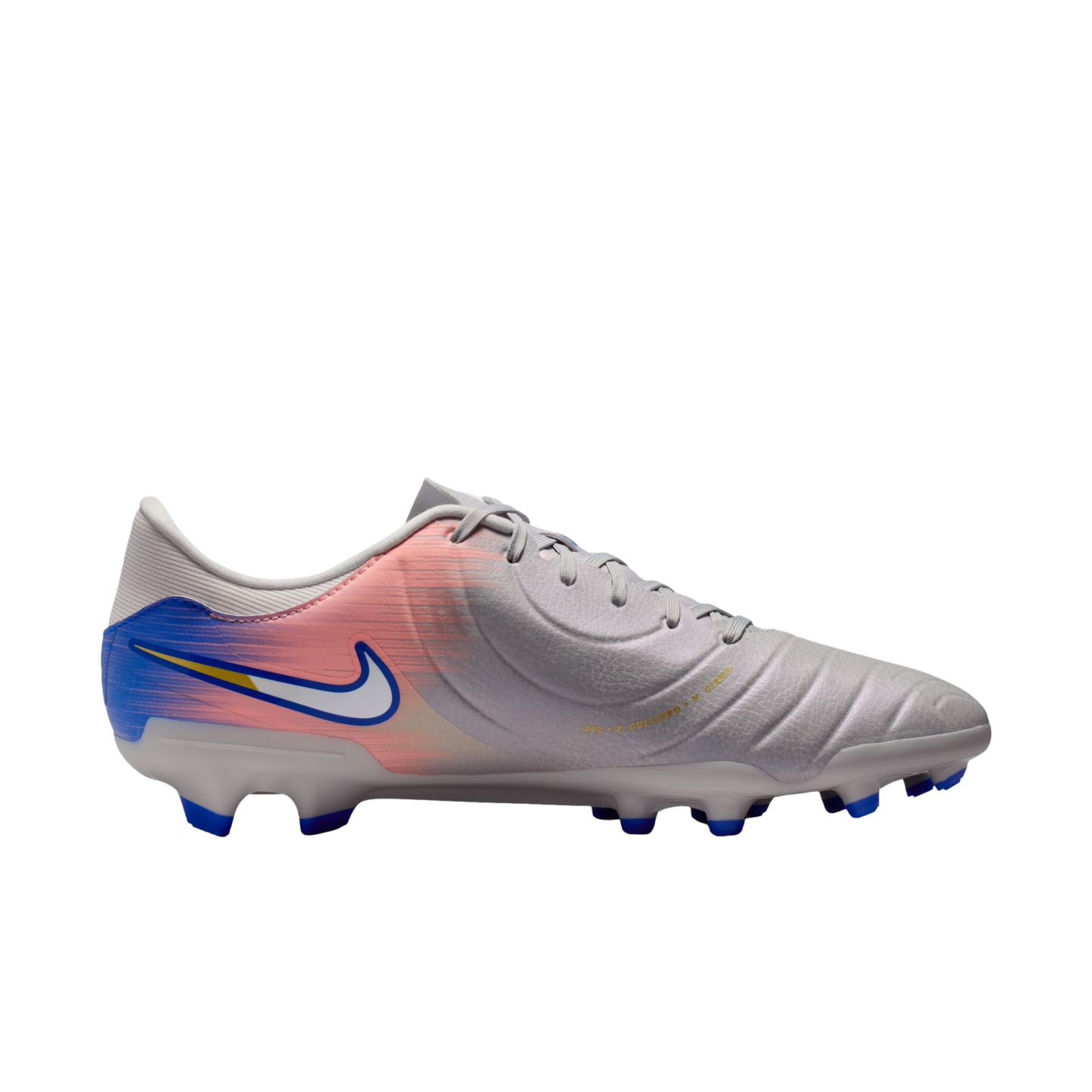 Side view of a light gray Nike soccer cleat with a pink and blue gradient design on the heel and blue studs, set against a black background.
