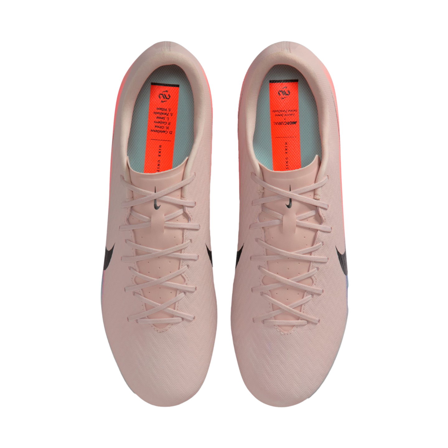 Top-down view of light pink Nike Mercurial soccer cleats with black swooshes and orange insoles, set against a black background.