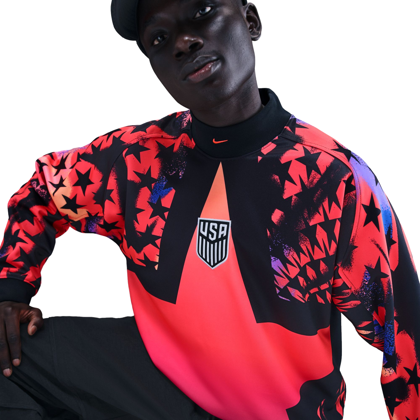 A person wearing a Nike USA soccer long-sleeve shirt featuring a bold red and black star pattern and the USA crest, set against a black background.
