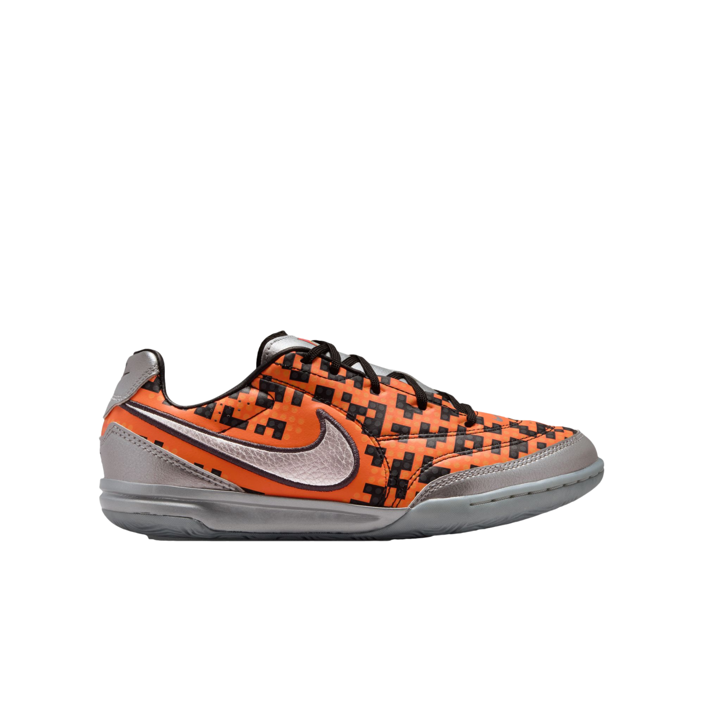 Side profile of an orange and black pixelated Nike indoor soccer shoe with metallic silver accents on a white background.