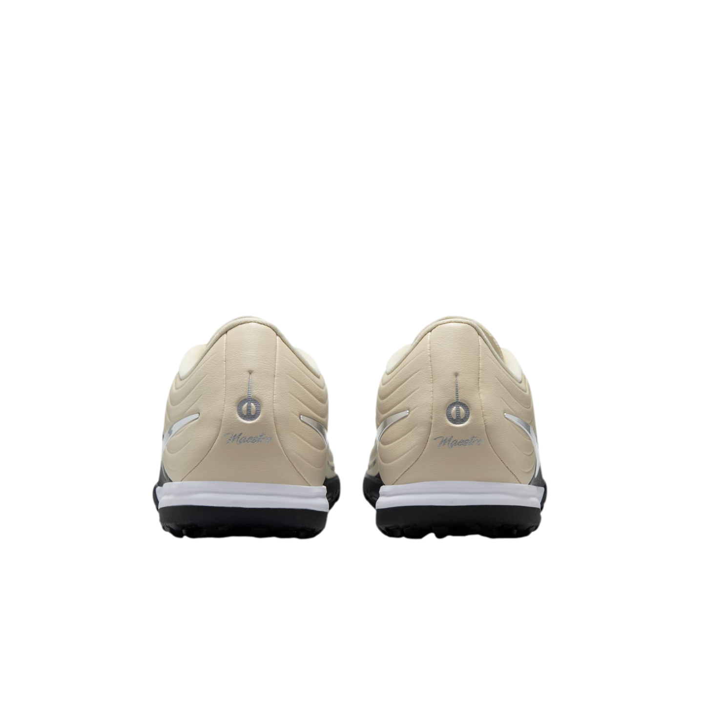 A rear view of two cream-colored turf shoes with silver logos and the word "Maestro" embossed on the heels. The shoes feature a white midsole and a black outsole against a solid black background.