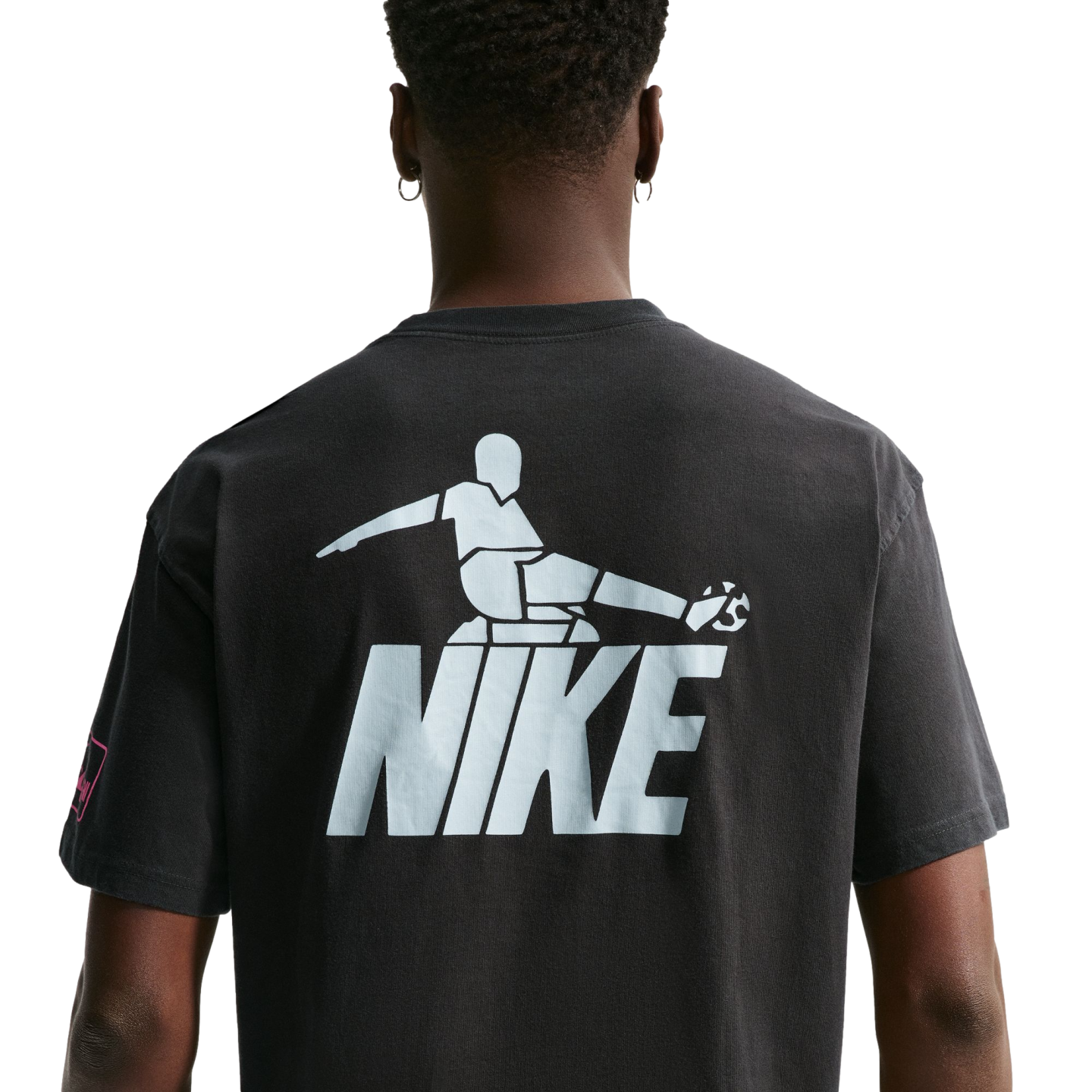 Rear view of a person wearing a dark t-shirt with a large light blue graphic of a stylized soccer player kicking a ball above the word "NIKE."