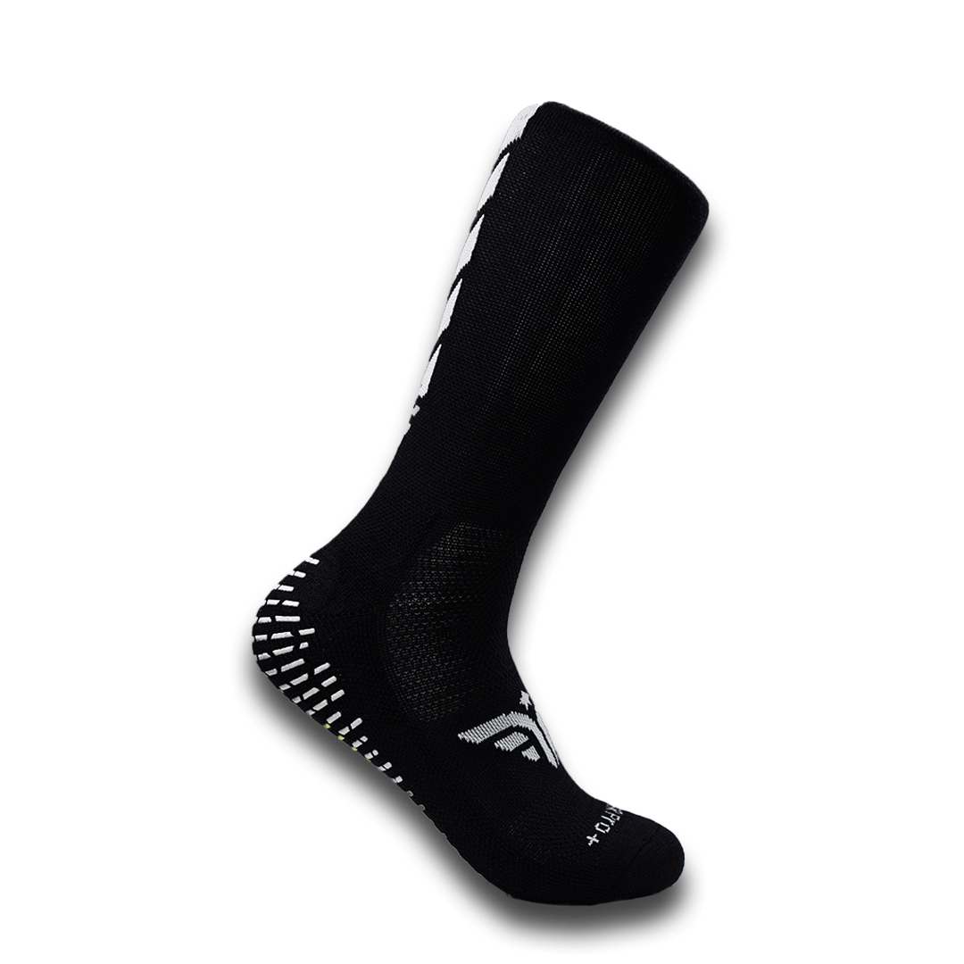 A black For The Footballer XLR8R Pro No Slip Sock featuring white logo details and rubberized grip pads on the heel and sole.