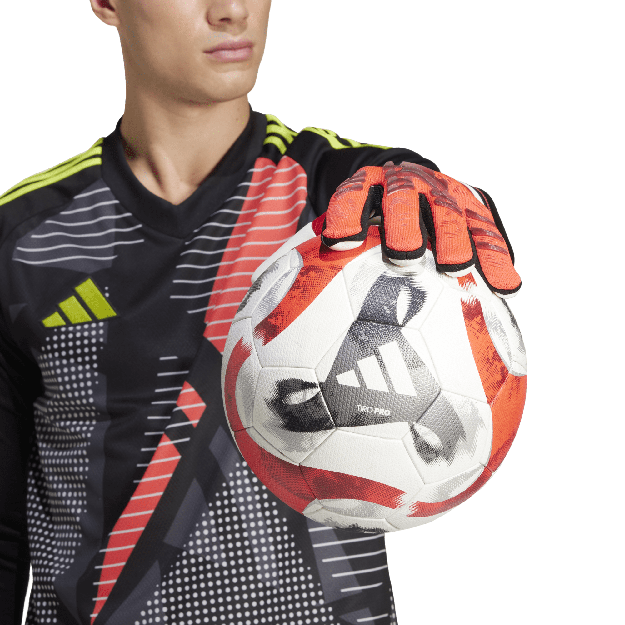 Goalkeeper in a black, red, and yellow jersey holding an Adidas Tiro Pro soccer ball with an orange-gloved hand against a green background.