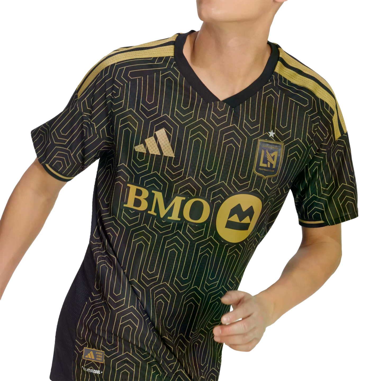 A person wears a black and gold Los Angeles FC soccer jersey featuring an Art Deco geometric pattern, the BMO sponsor logo, and the team crest.