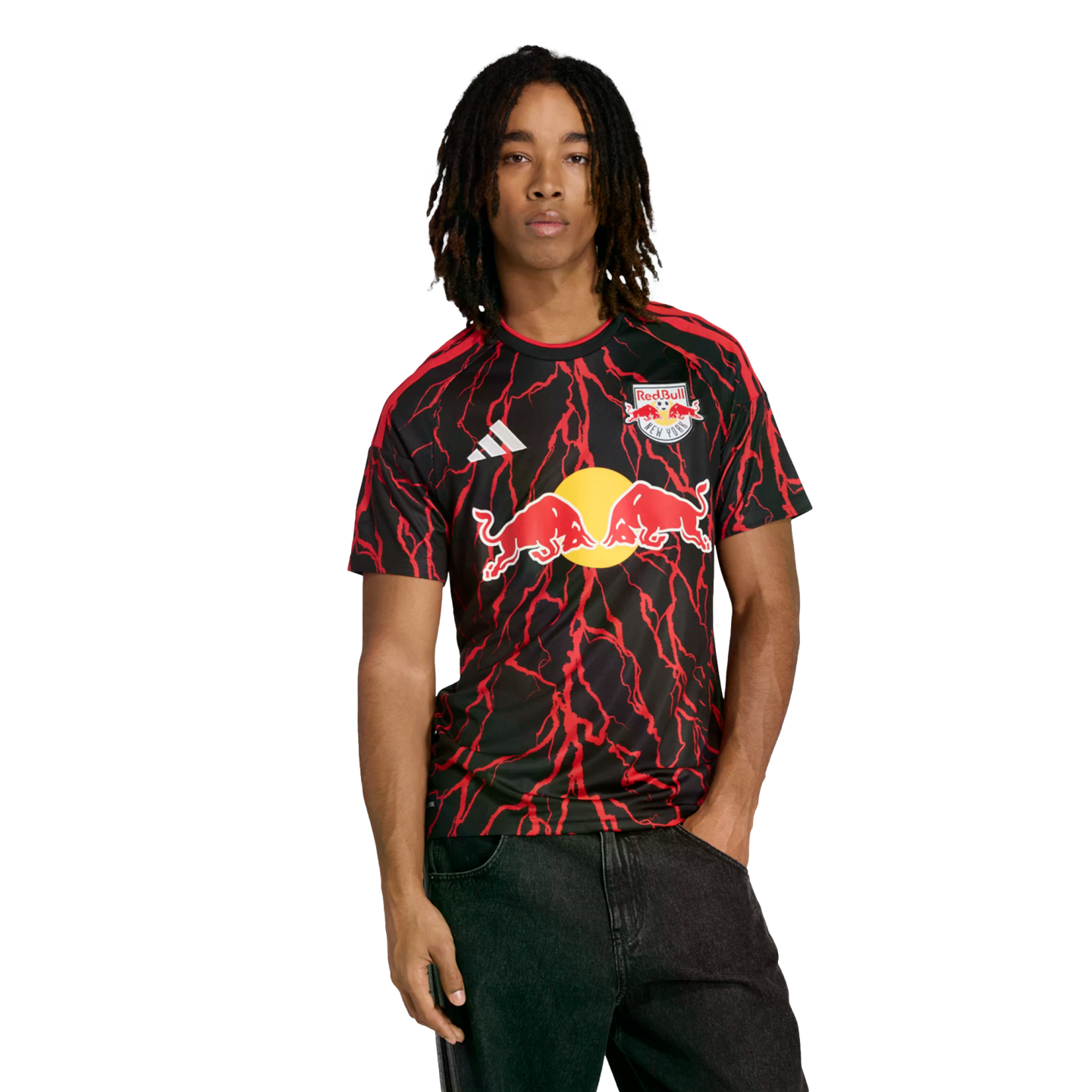 A man wearing a New York Red Bulls soccer jersey with red lightning patterns and black jeans against a black background.