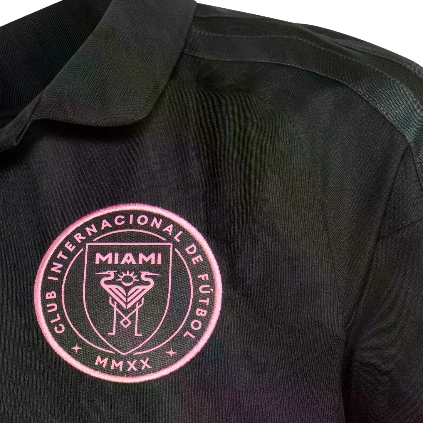 Close-up of a black Inter Miami CF soccer jersey featuring a pink embroidered team crest on the chest.