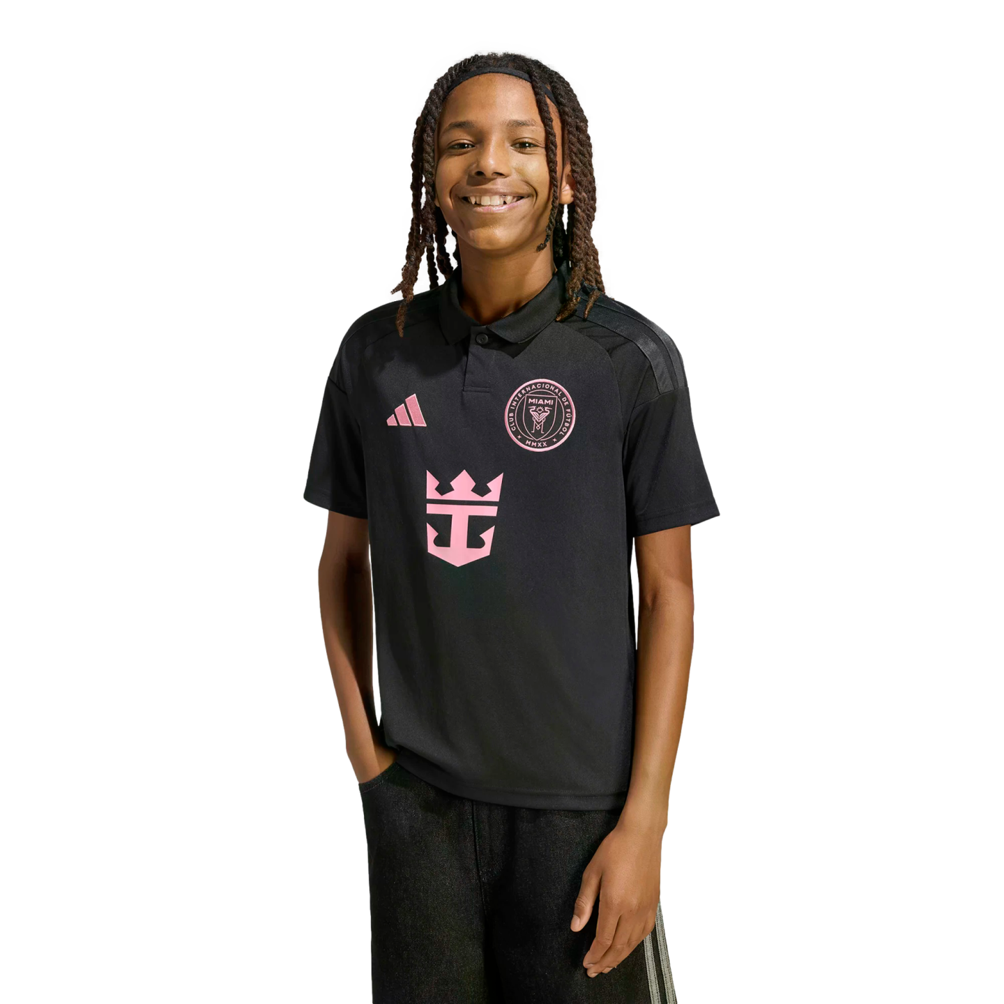 A smiling person with dreadlocks wearing a black Inter Miami CF soccer polo shirt with pink logos, set against a solid black background.