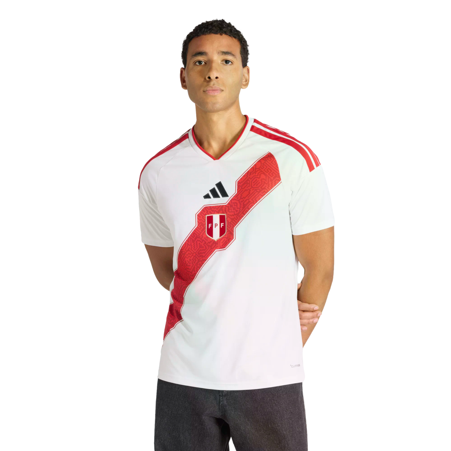 Man wearing a white Peru national soccer team jersey with a red patterned diagonal sash and Adidas logo, standing against a black background.
