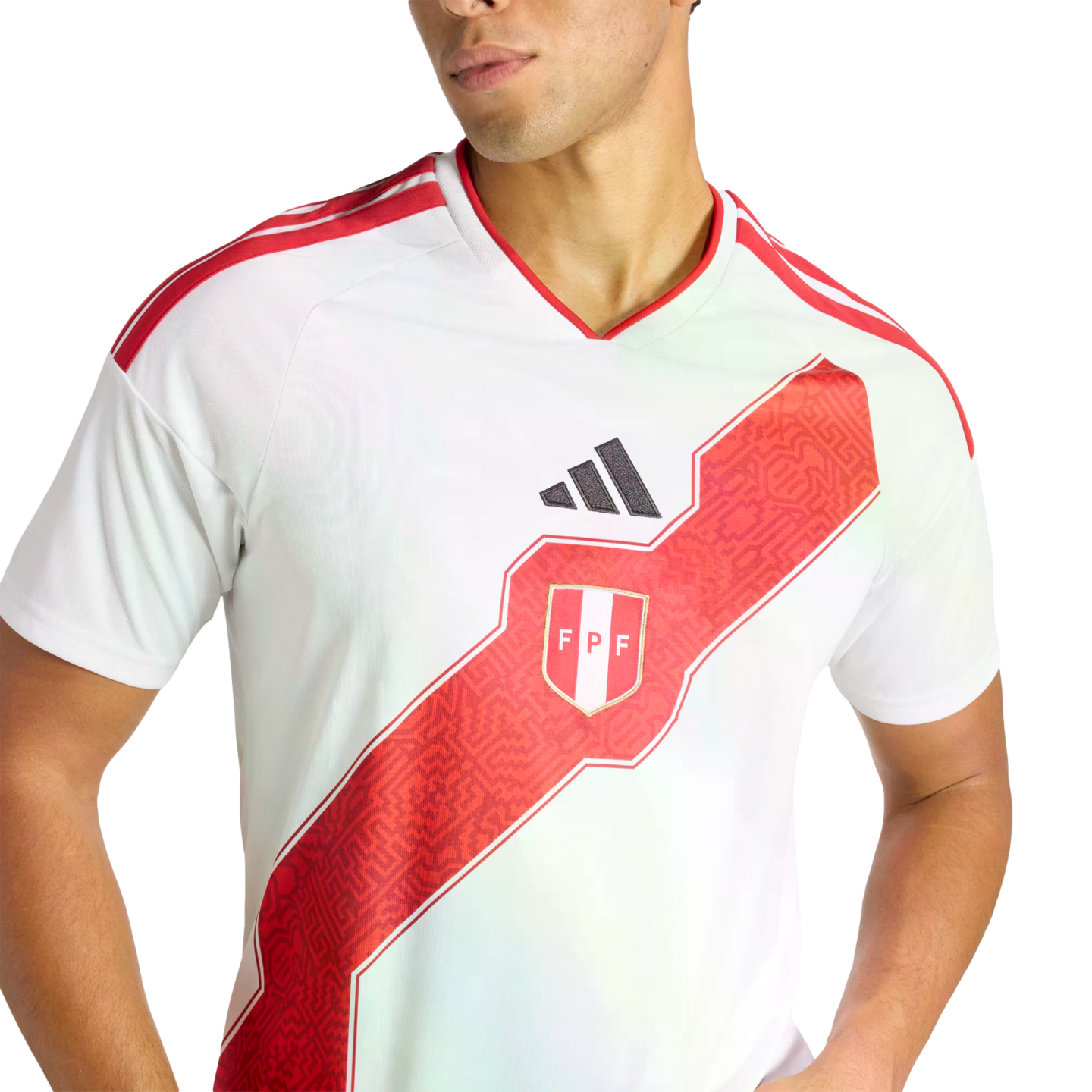 A person wearing the white Peru national soccer team home jersey, featuring a prominent red diagonal sash with geometric patterns and the team's crest.