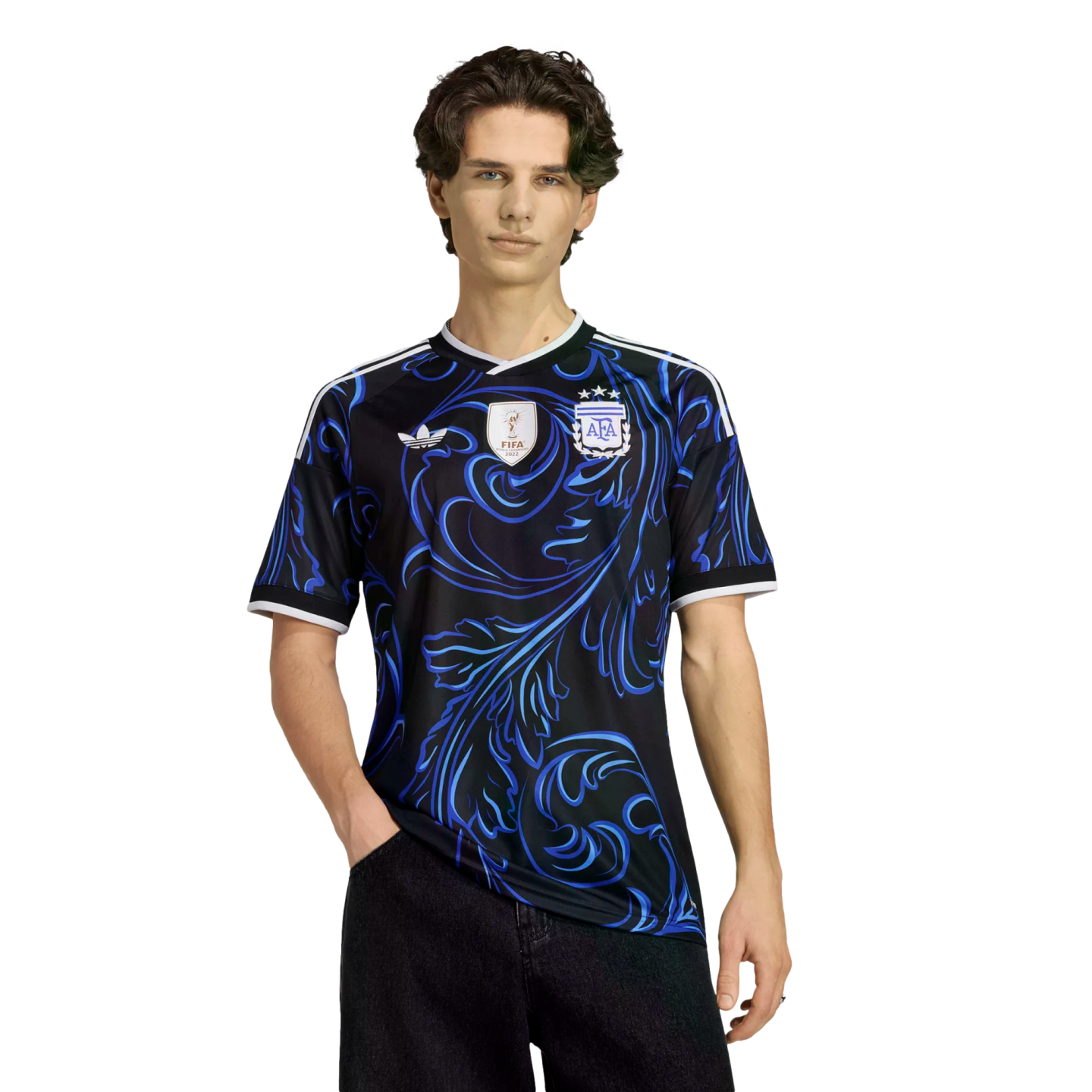 Young man modeling a black Adidas Argentina jersey with a blue swirl pattern, FIFA World Cup champions patch, and AFA crest.