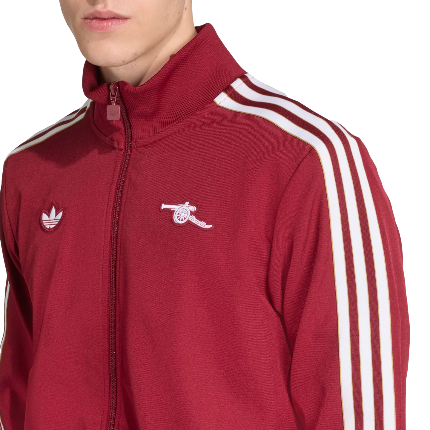 A person wears a maroon Adidas track jacket featuring three white stripes on the sleeves and the Arsenal FC cannon logo on the left chest.