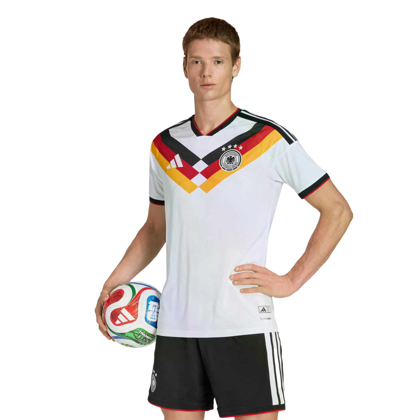 A person in a German national team soccer uniform poses with a soccer ball against a black background.