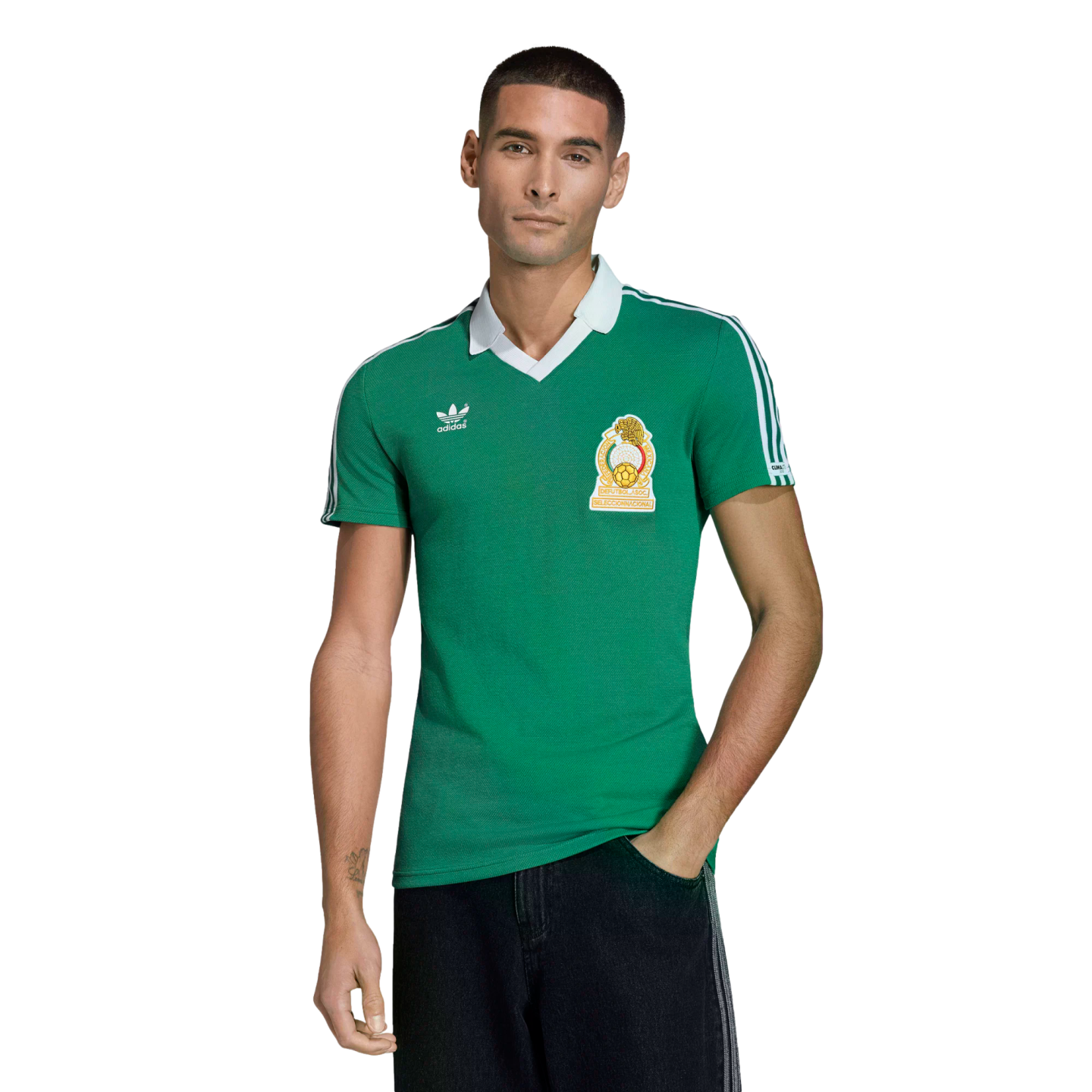 A man models a green Mexico national team soccer jersey with white trim and an Adidas logo against a solid black background.