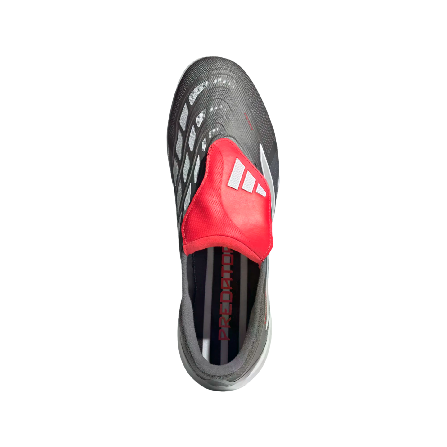 Top-down view of a grey Adidas Predator soccer cleat with a vibrant red fold-over tongue and white stripes against a black background.