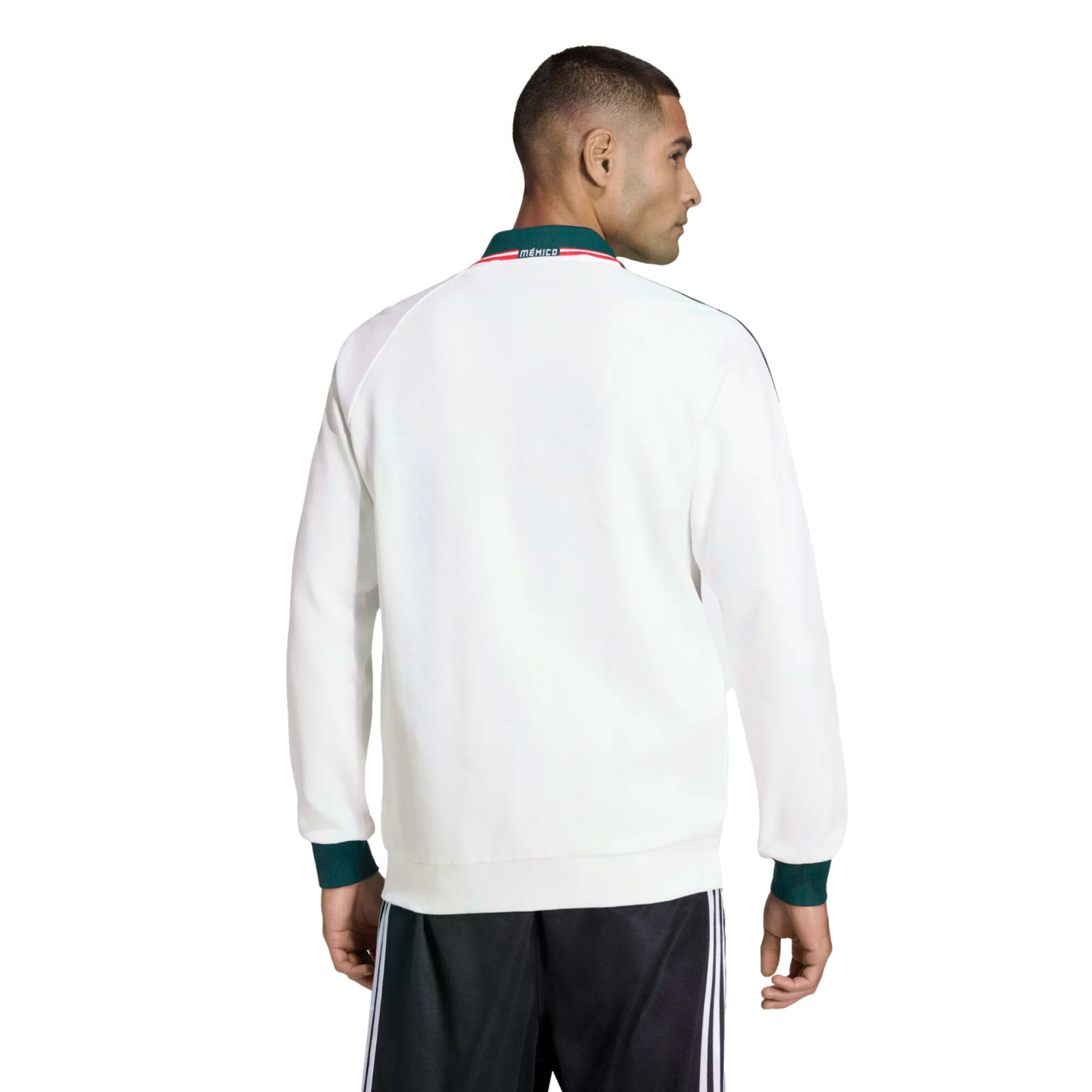 Rear view of a man in a white track jacket with green cuffs and a 'MÉXICO' collar, paired with black track pants against a black background.
