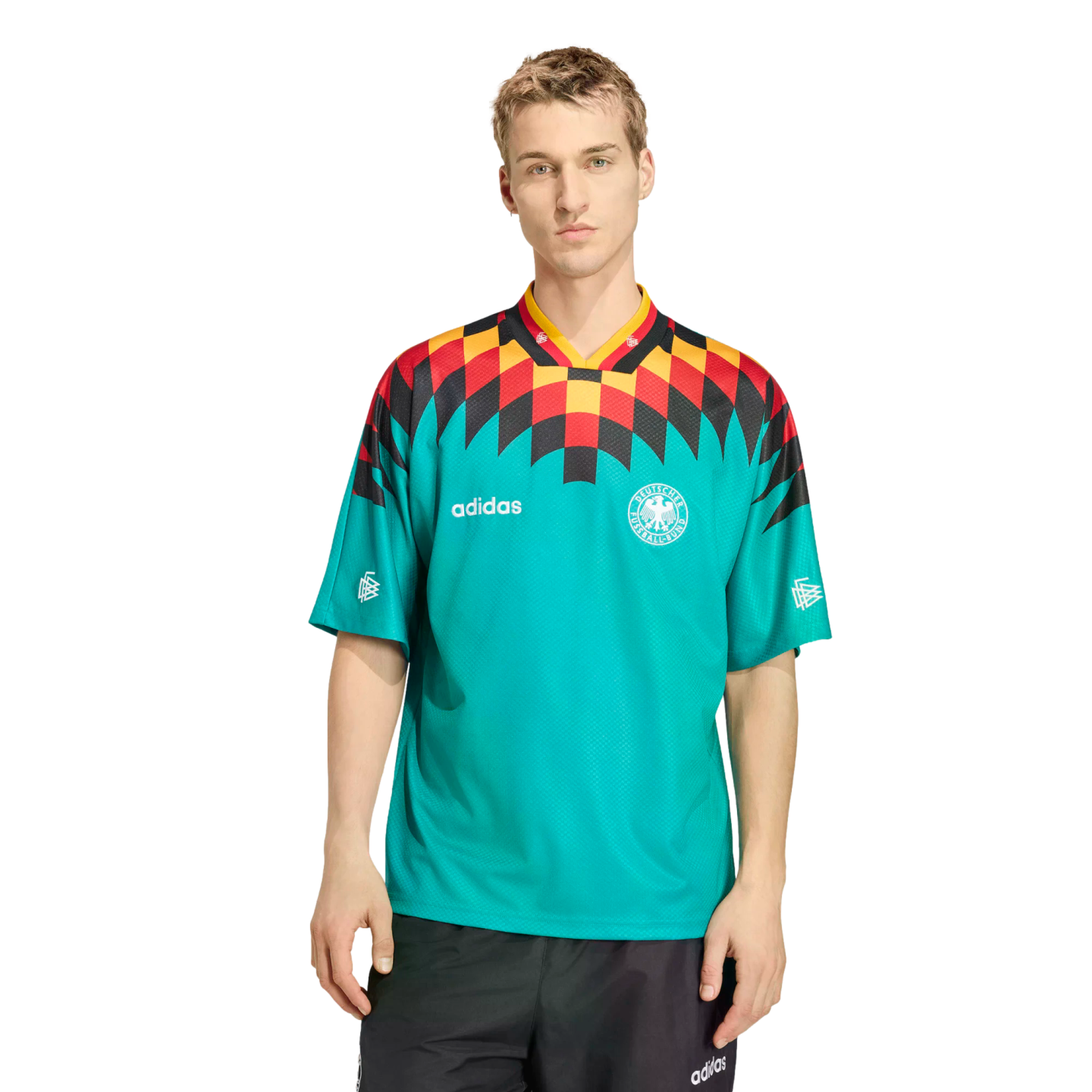 A man models a teal Adidas Germany soccer jersey with a bold black, red, and yellow geometric shoulder pattern, paired with black athletic shorts against a white background.