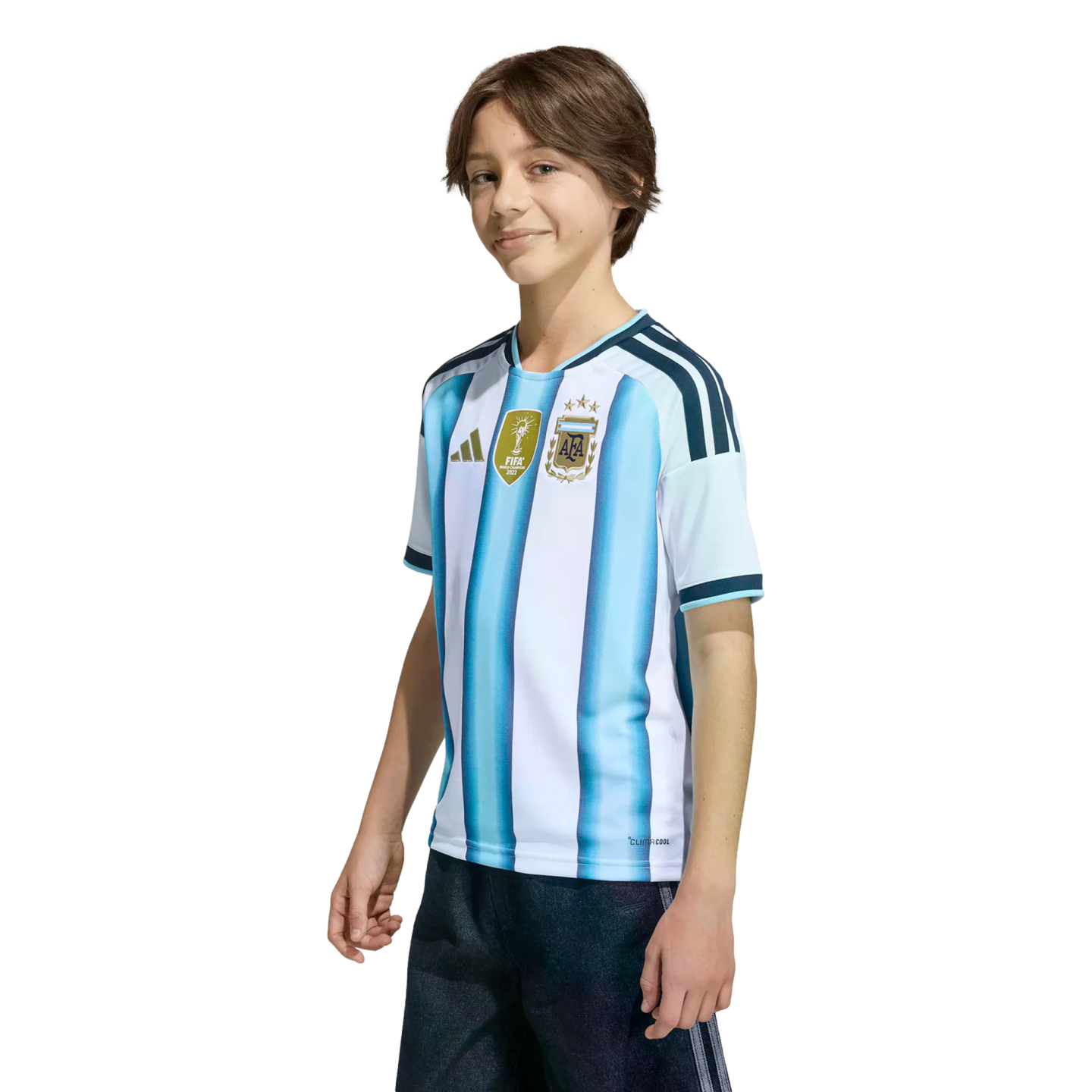 A smiling boy wearing an Argentina national football team jersey with the FIFA World Champions 2022 patch, set against a black background.