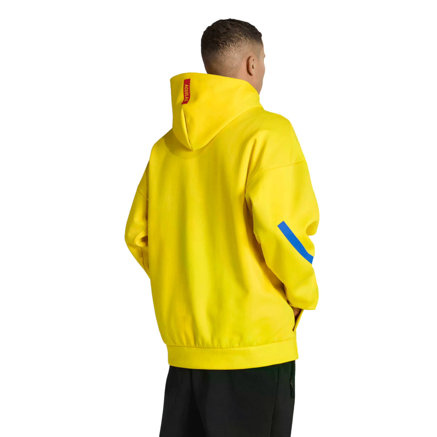 Rear view of a man in a bright yellow hoodie with a red tag and blue sleeve stripe, wearing black pants against a solid black background.