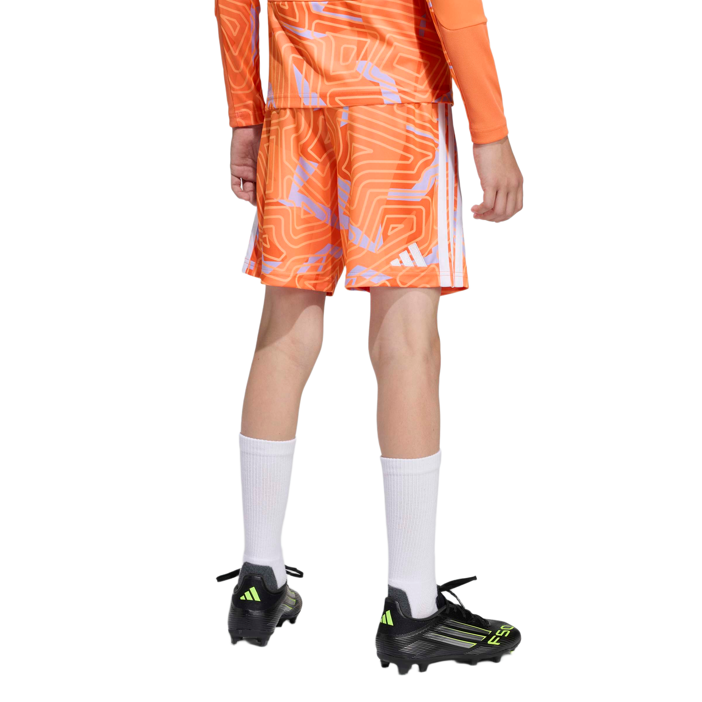 Rear view of a person wearing orange patterned soccer shorts and jersey, high white socks, and black soccer cleats against a plain white background.