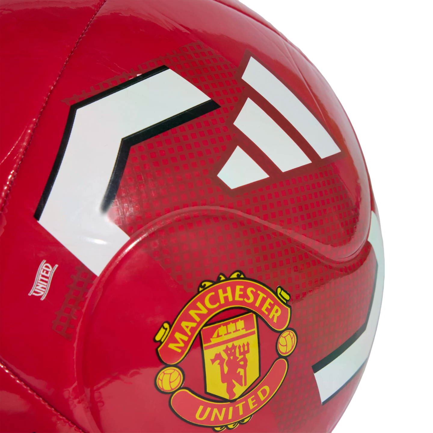 Close-up of a glossy red soccer ball featuring the Manchester United club crest and white Adidas stripes against a textured red background.