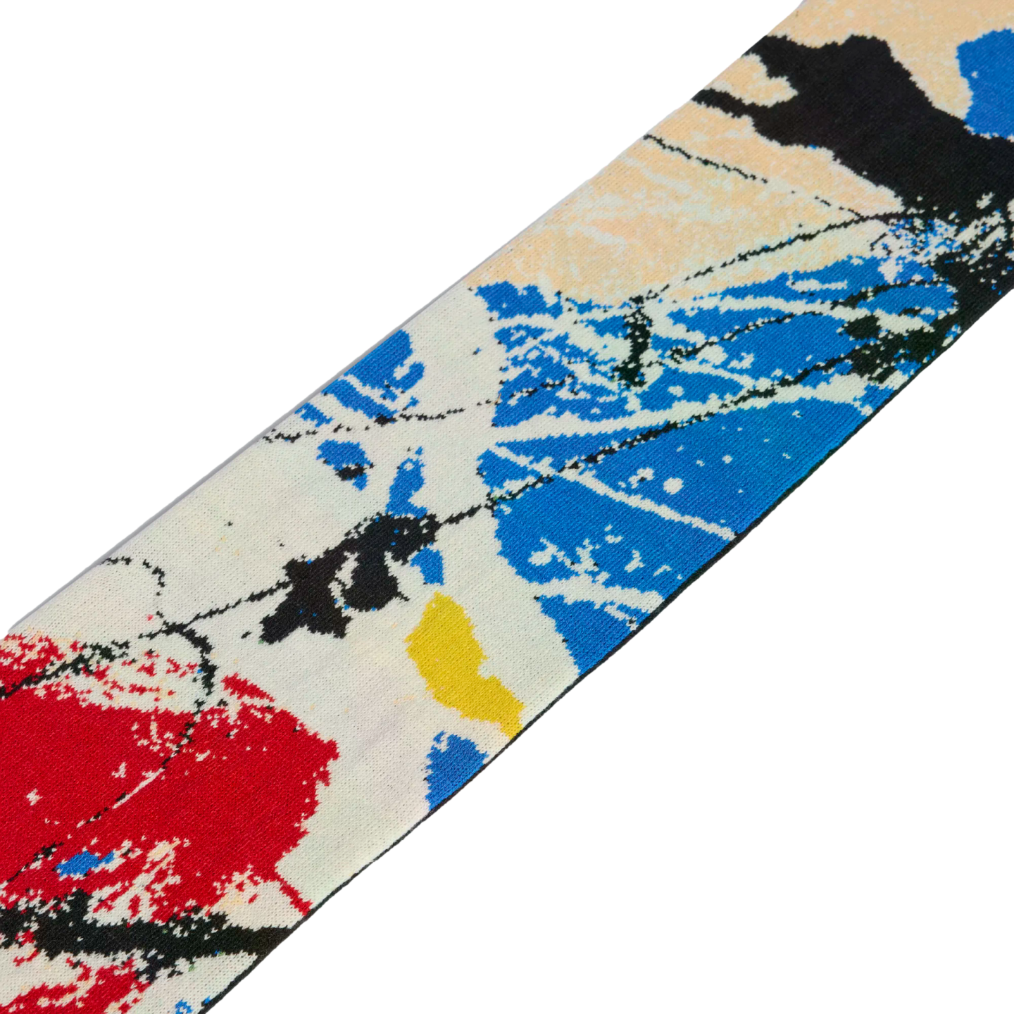 A diagonal strip of knit fabric featuring an abstract paint-splatter pattern in red, blue, yellow, and black on an off-white base.