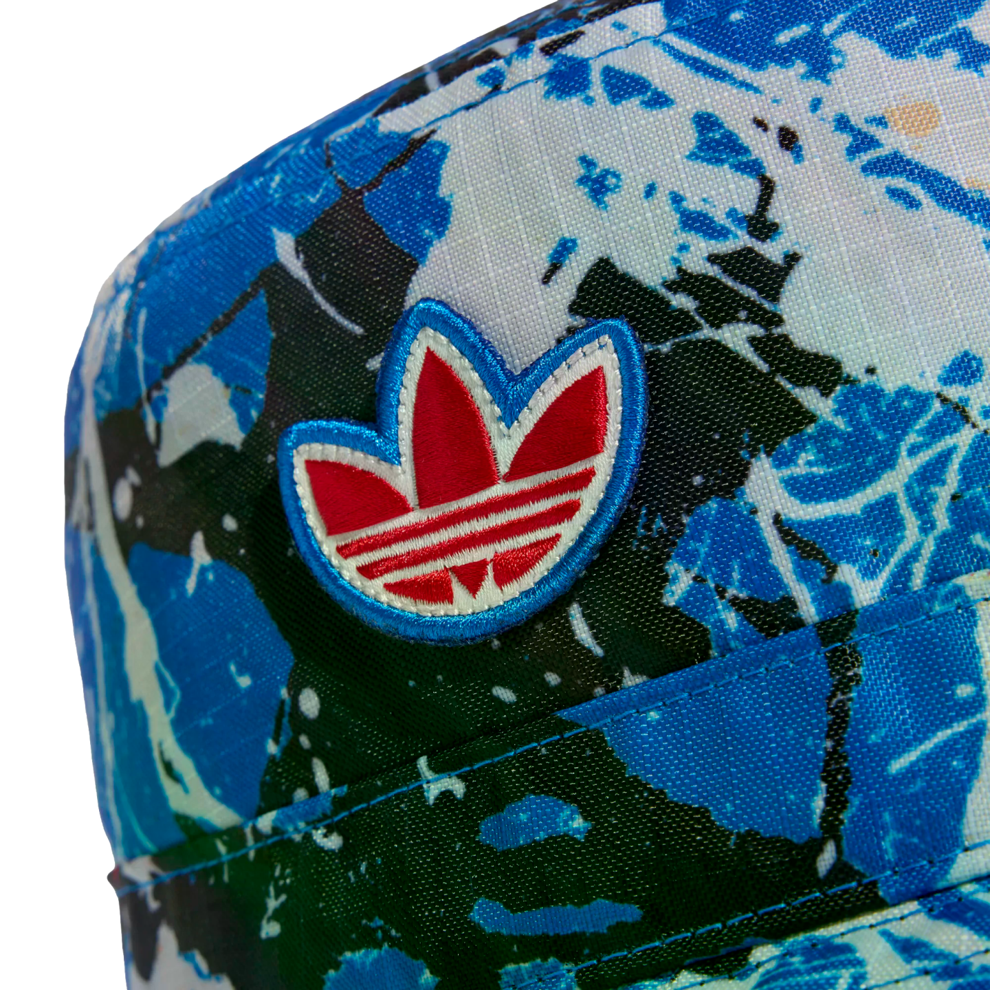 Close-up of an Adidas cap featuring an abstract blue and white splatter pattern and an embroidered red and white Trefoil logo.