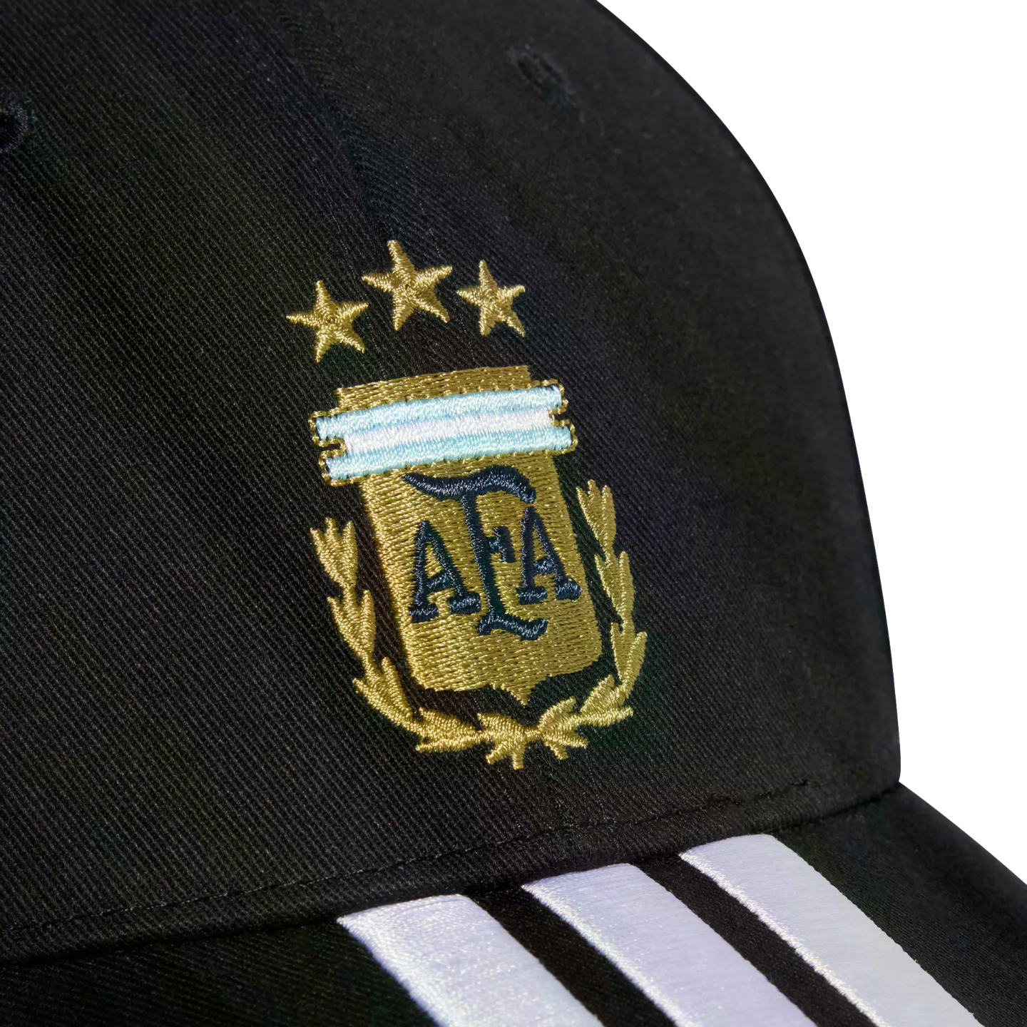 Close-up of a black cap with the gold embroidered Argentina (AFA) crest, three stars above it, and three white stripes on the brim.