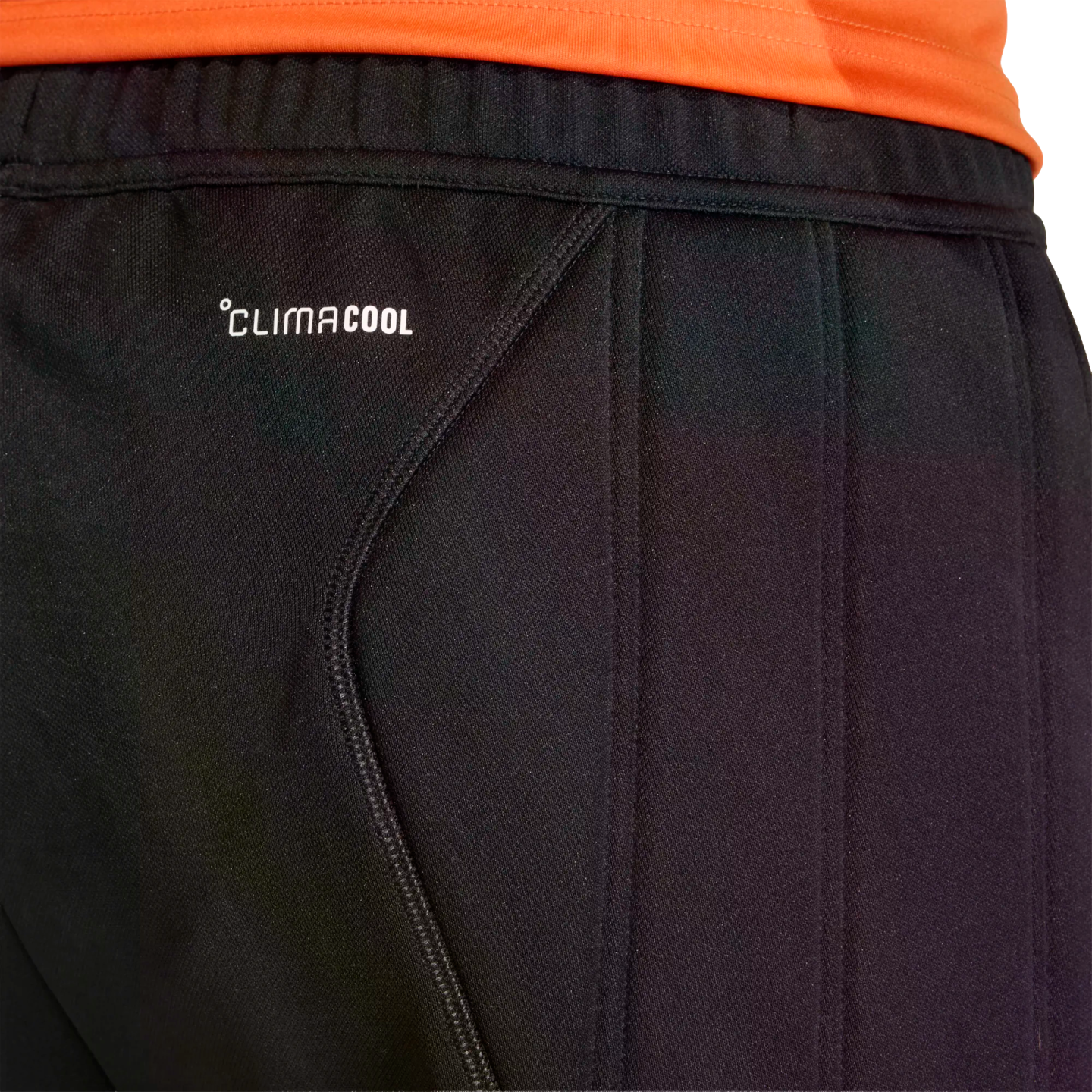 Close-up of black Adidas ClimaCool athletic pants with an orange shirt visible at the top waistband.
