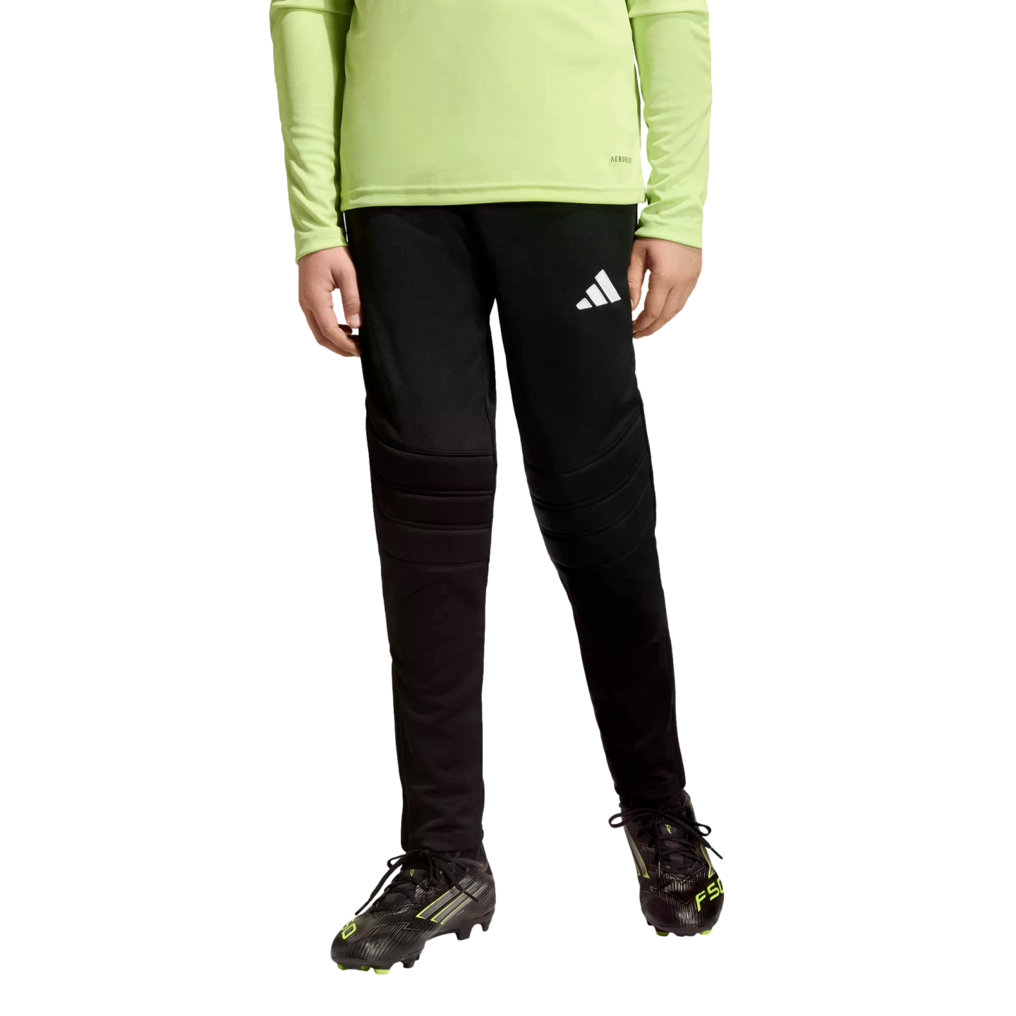 Person wearing a lime green long-sleeve shirt, black padded soccer pants, and black cleats against a black background.