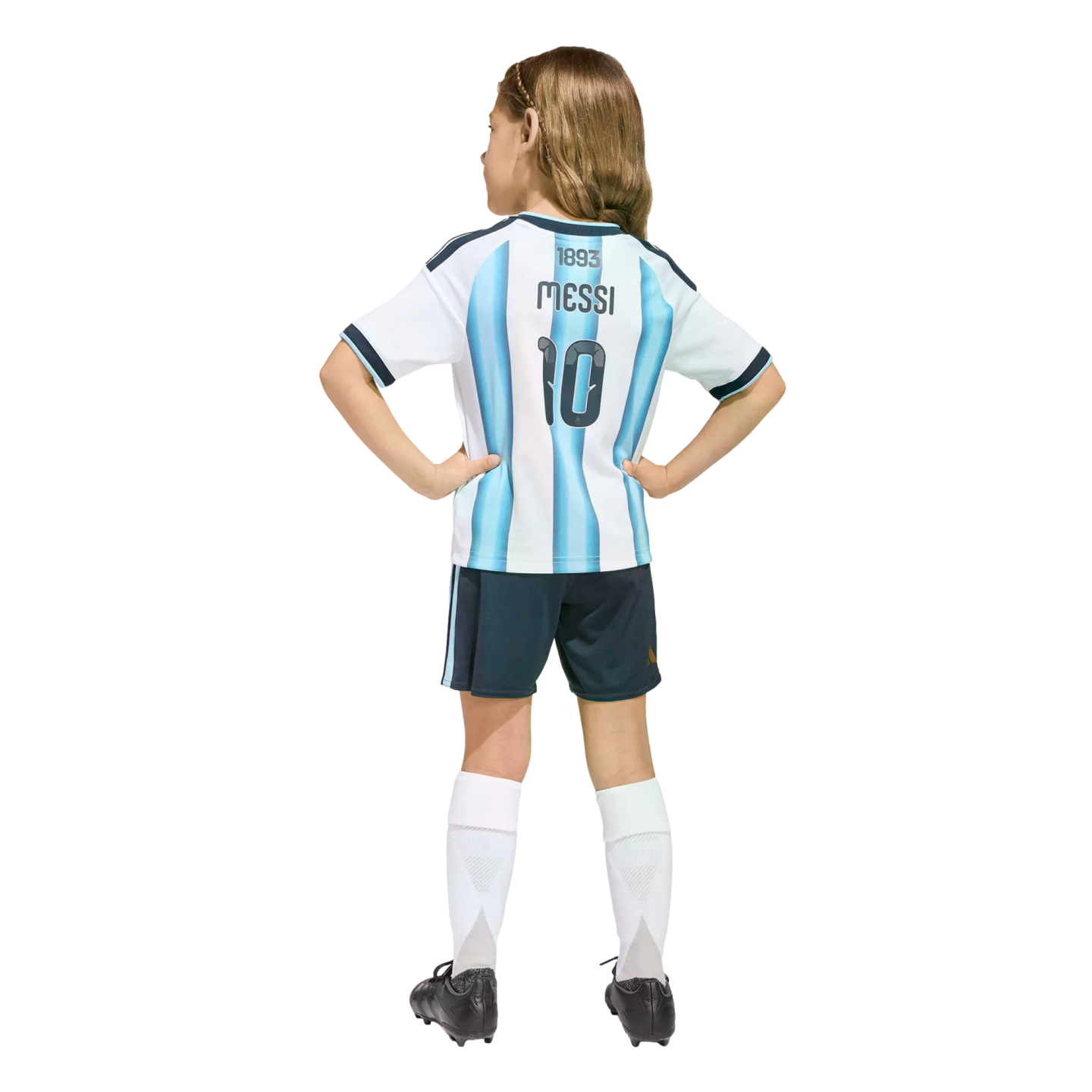 Back view of a child in a light blue and white striped Messi #10 soccer jersey, dark shorts, and white socks, standing against a black background.