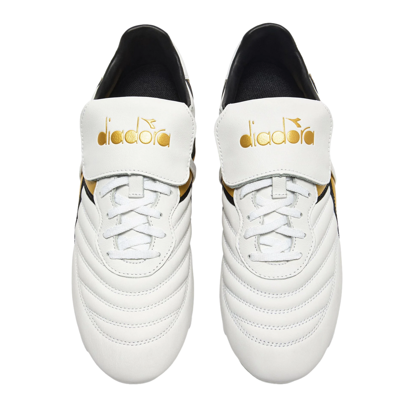 Top-down view of white Diadora soccer cleats with quilted uppers and gold branding on large fold-over tongues, against a black background.