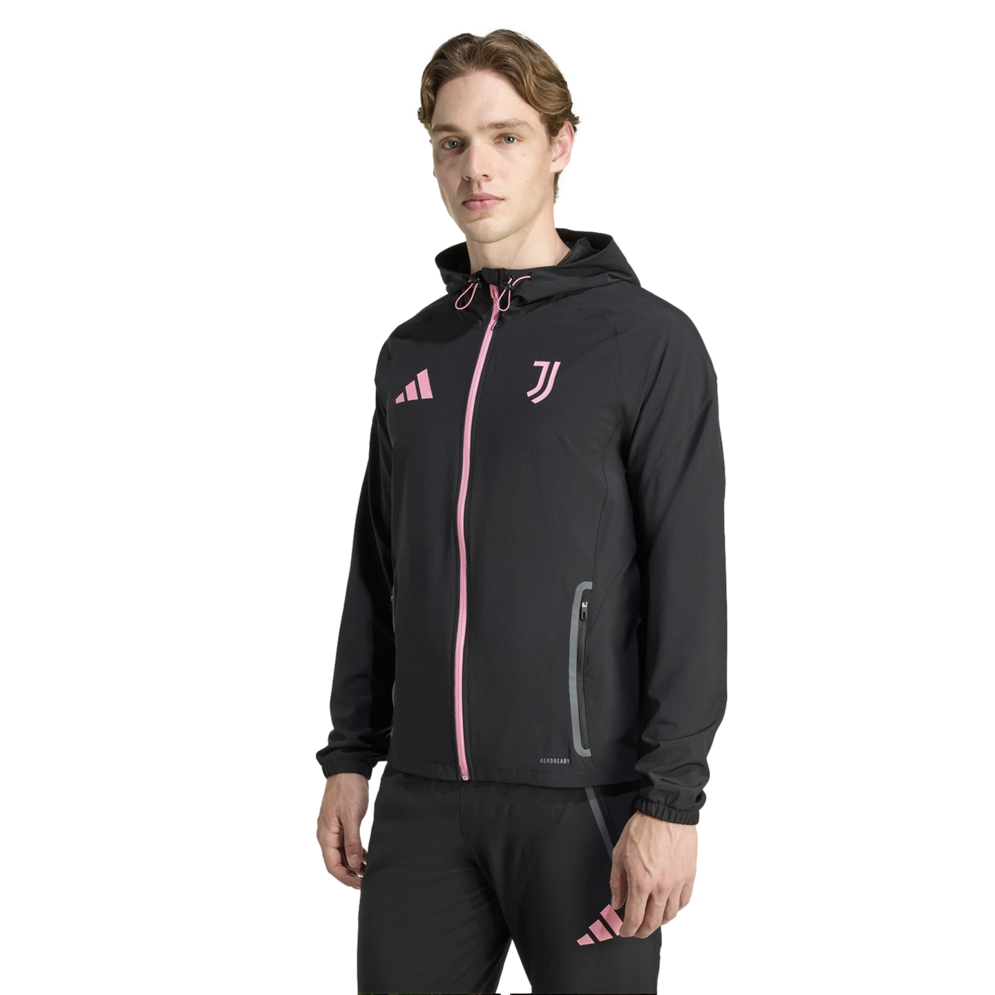 A young man wearing a black Adidas Juventus hooded track suit with pink logos and accents, standing against a solid black background.