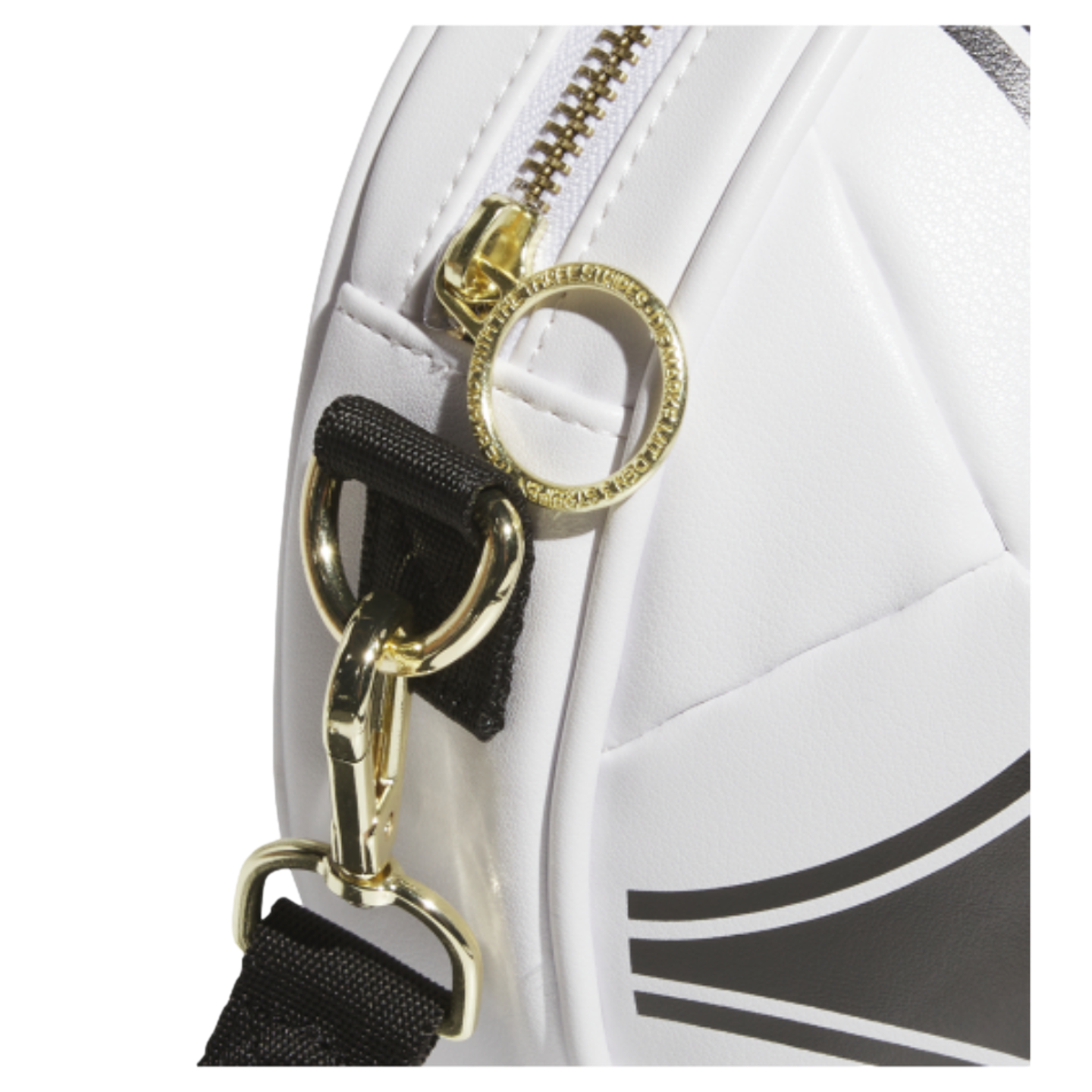 Close-up of a white bag showing gold hardware, a circular zipper pull with text, and a black shoulder strap attached by a gold hook.