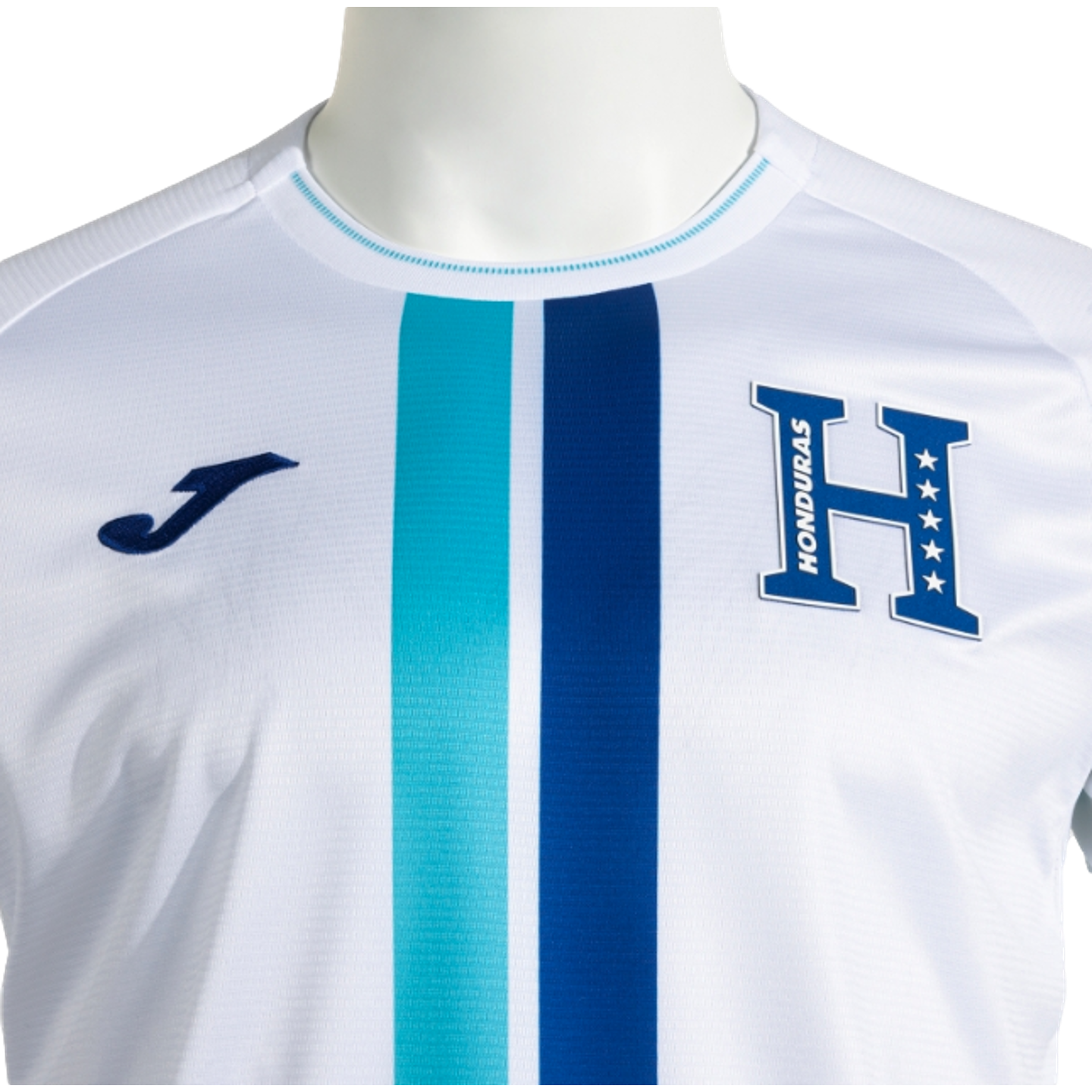 Close-up of a white Joma Honduras national team jersey with central turquoise and navy blue vertical stripes and a large blue 'H' emblem featuring five stars and the word "HONDURAS."