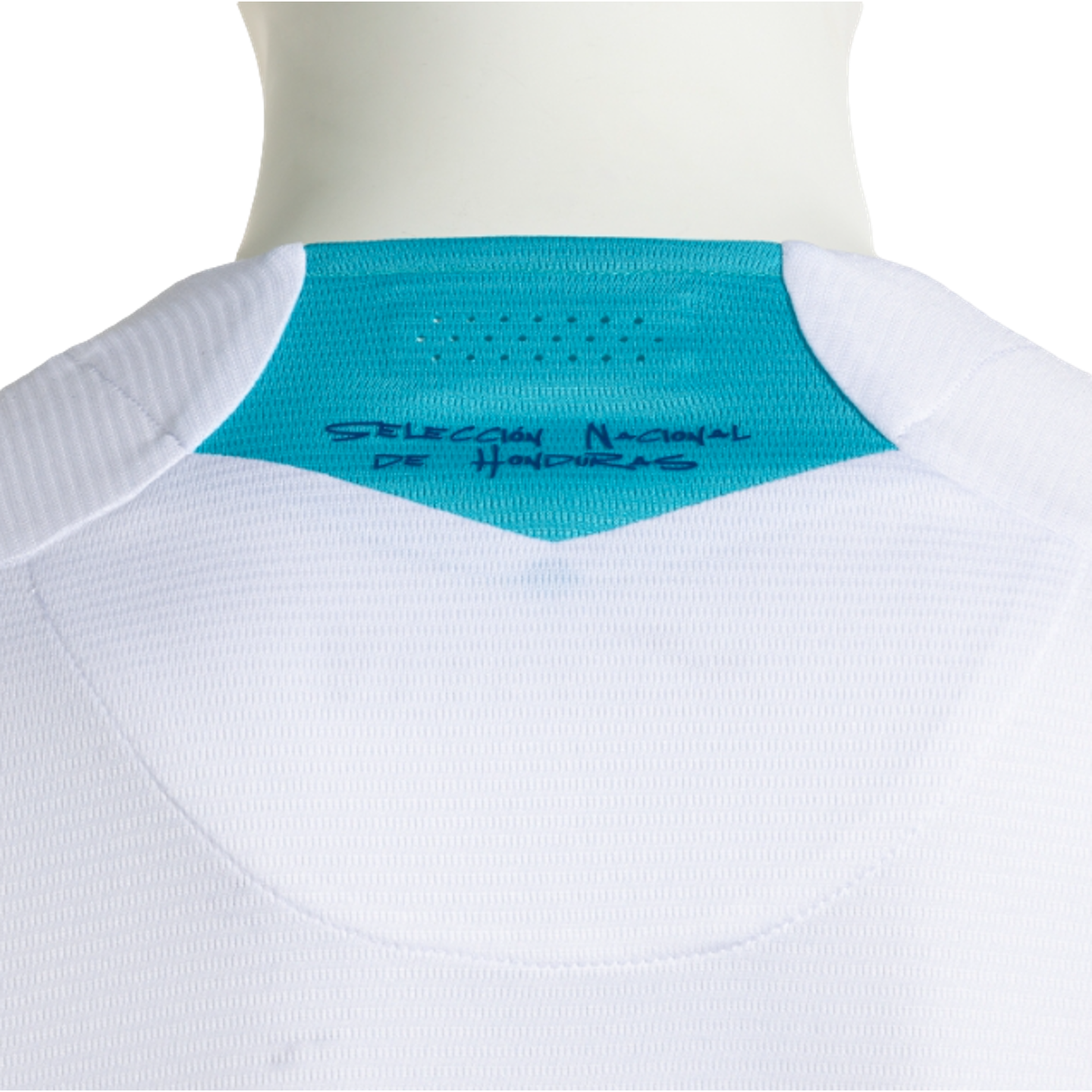 A close-up of the back of a white textured sports jersey, featuring a bright turquoise triangular panel at the nape of the neck. The panel contains small ventilation holes and dark blue handwritten-style text that reads "SELECCIÓN NACIONAL DE HONDURAS."